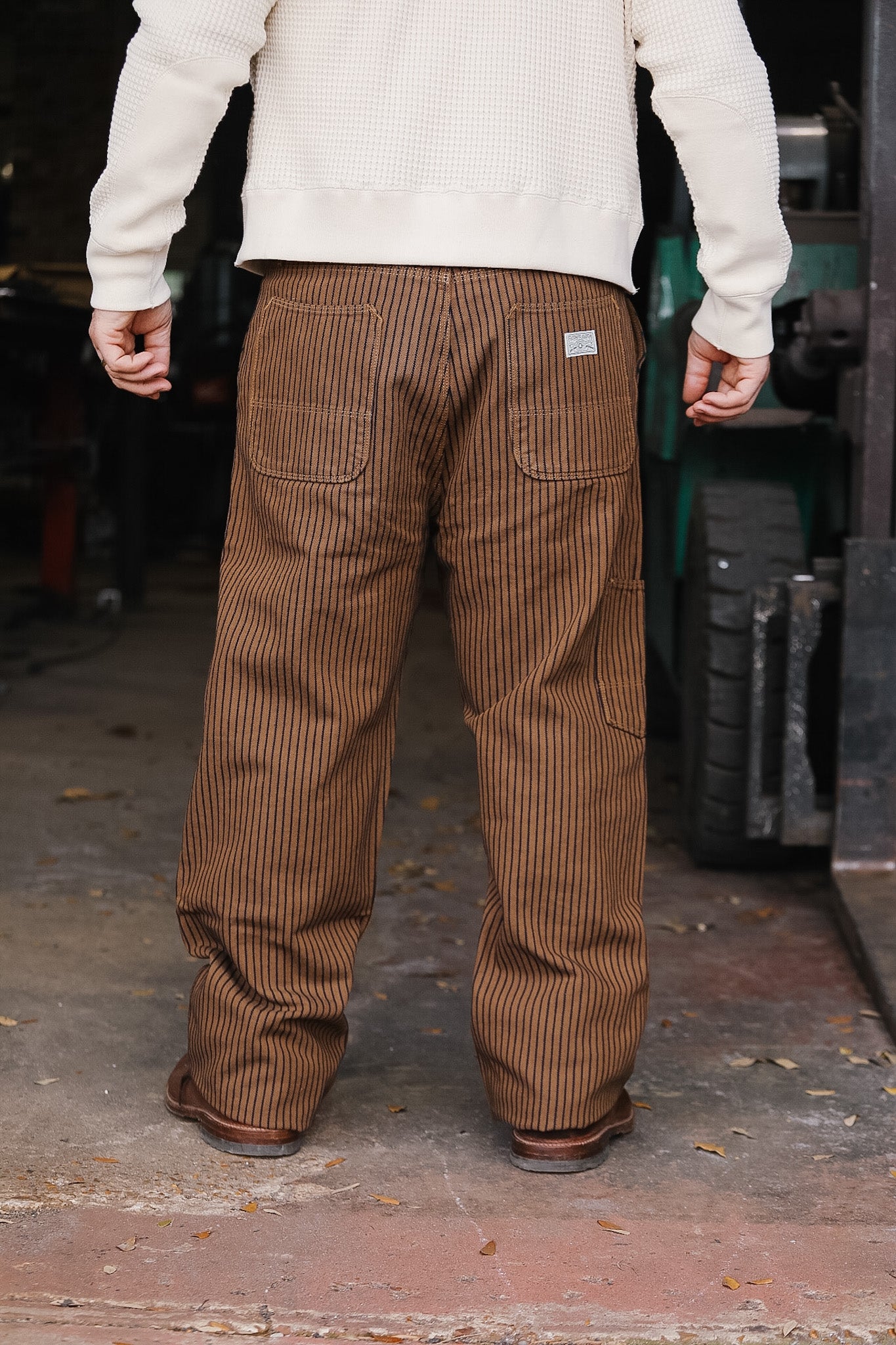 Person wearing brown corduroy pants with a visible brand logo in an outdoor setting.