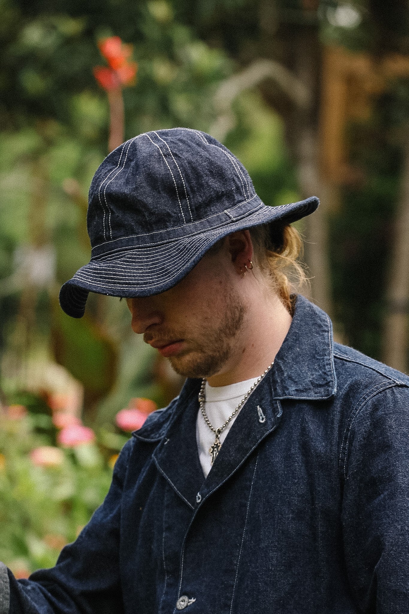 Man wearing a denim cap and jacket outdoors with blurred background