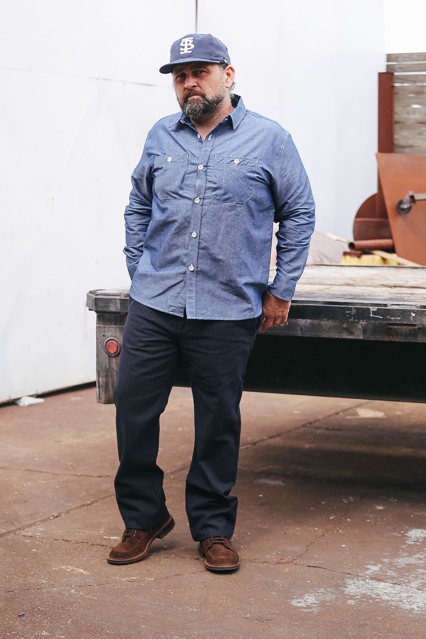 Man wearing a blue shirt and cap standing in front of a truck