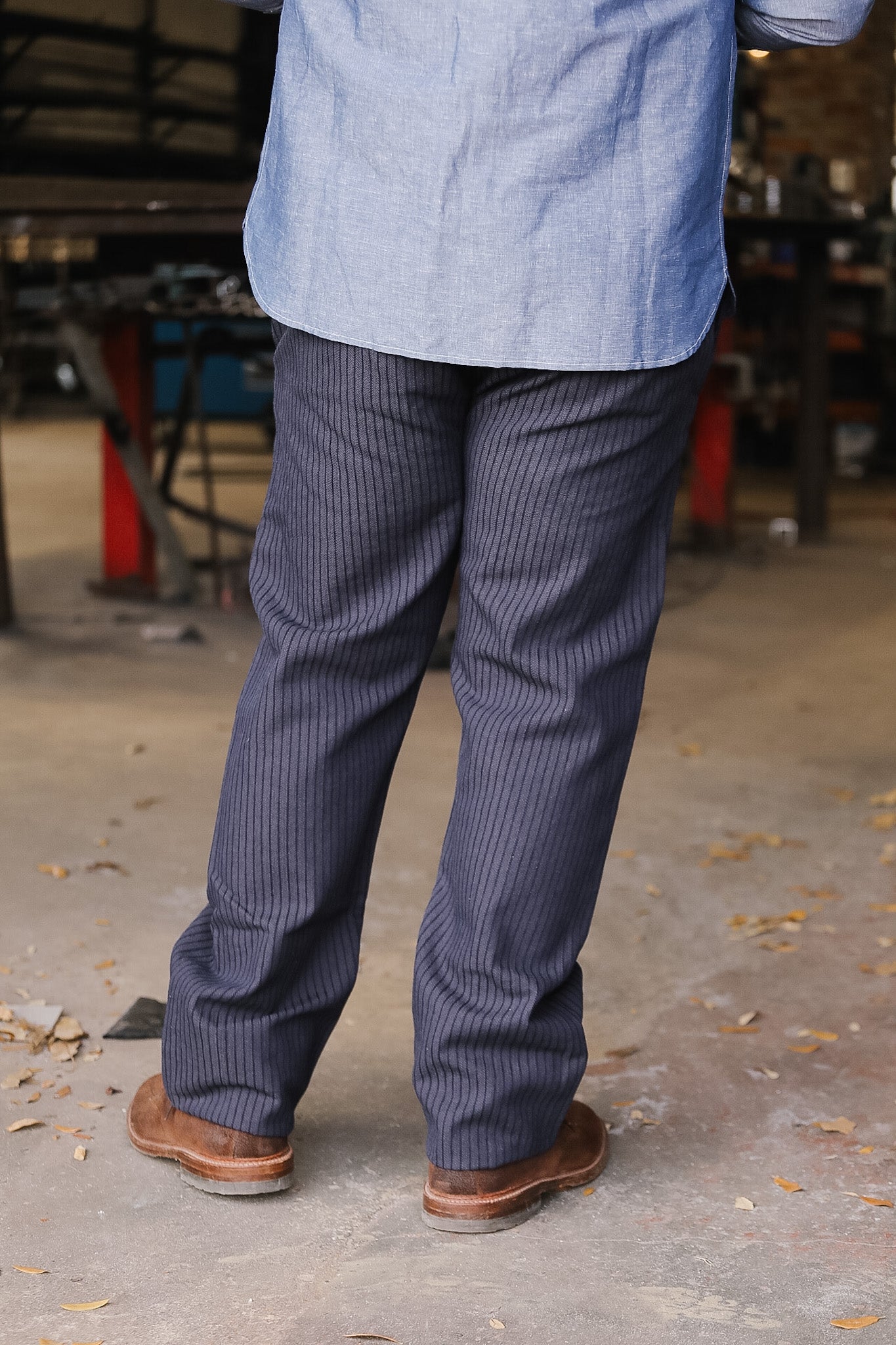 Person wearing a blue shirt and dark pinstripe pants on a concrete floor.