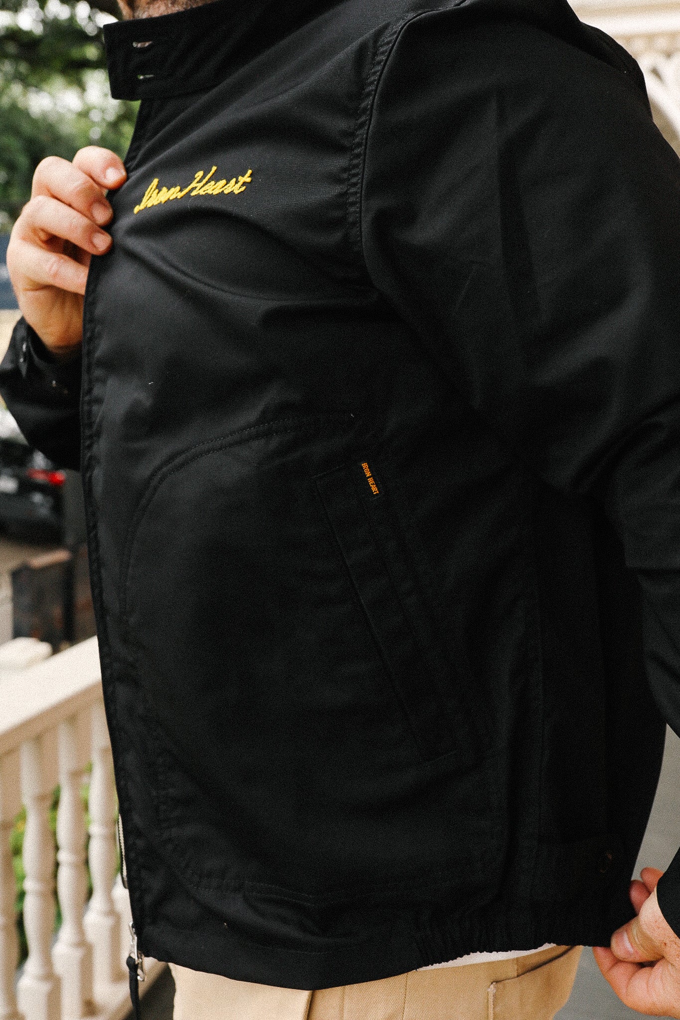 Black jacket with yellow branding on a blurred outdoor background