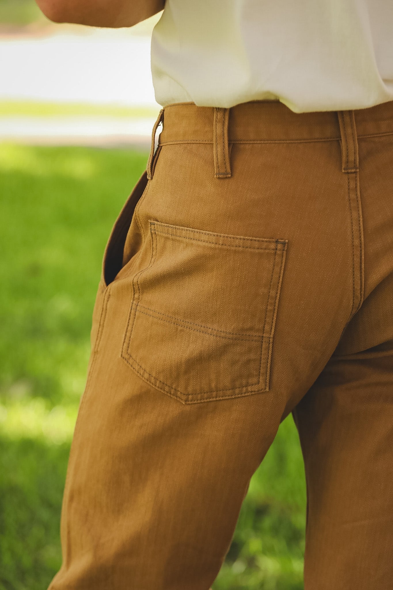 Brown pants with a pocket detail against a blurred green background