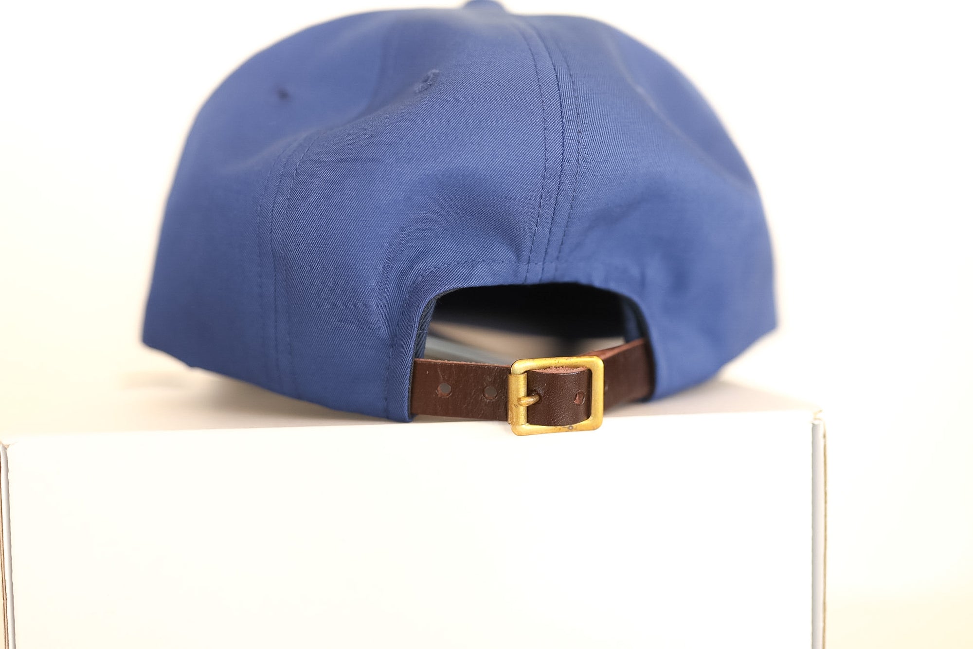 Blue cap with a brown strap and gold buckle on a white background