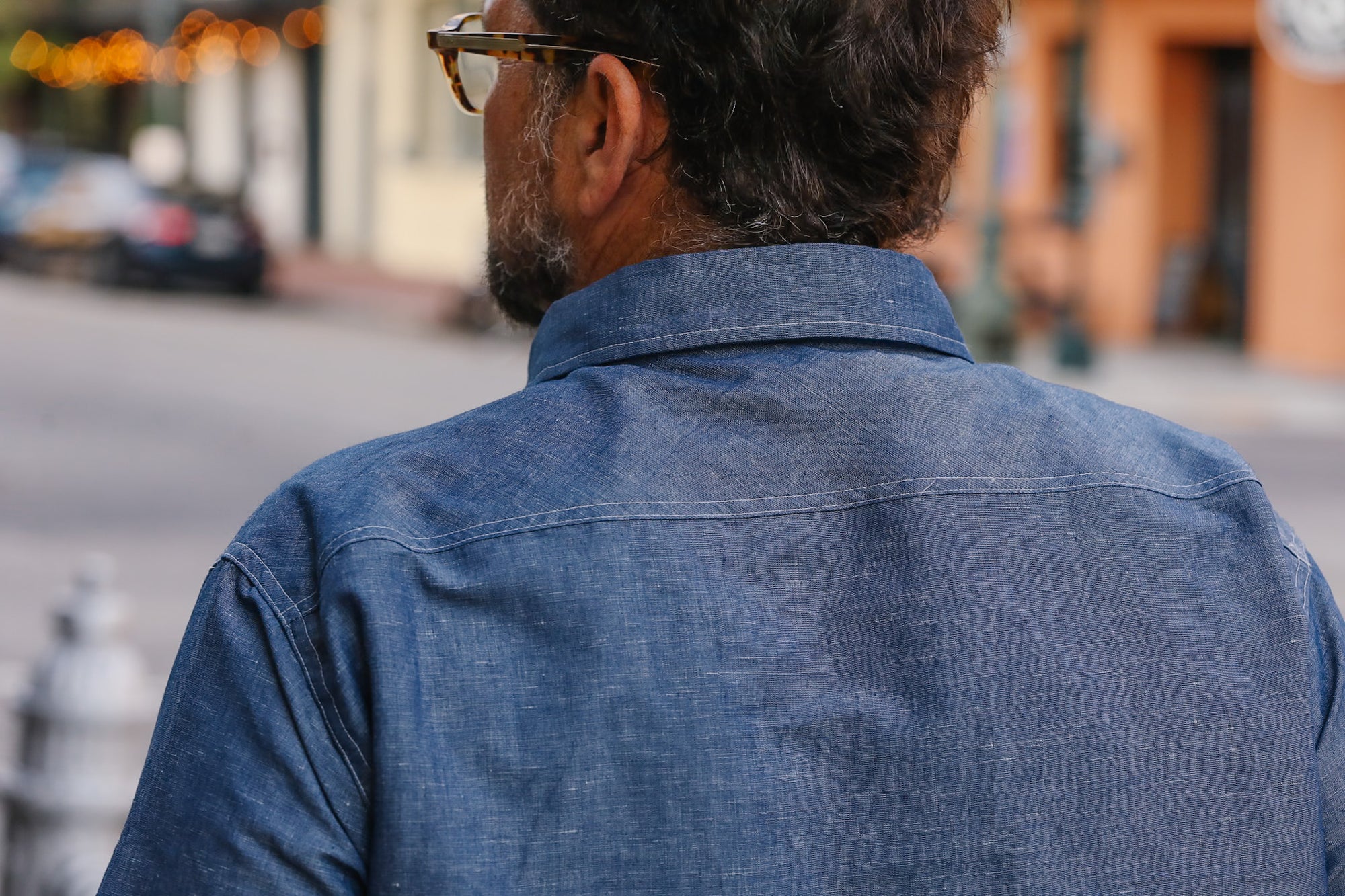 Man wearing a blue denim shirt walking on a street