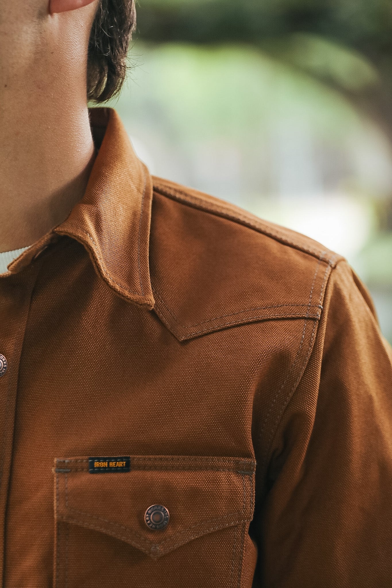 Close-up of a person wearing a brown corduroy overshirt with a chest pocket and a small visible 'Blue Wing' label.