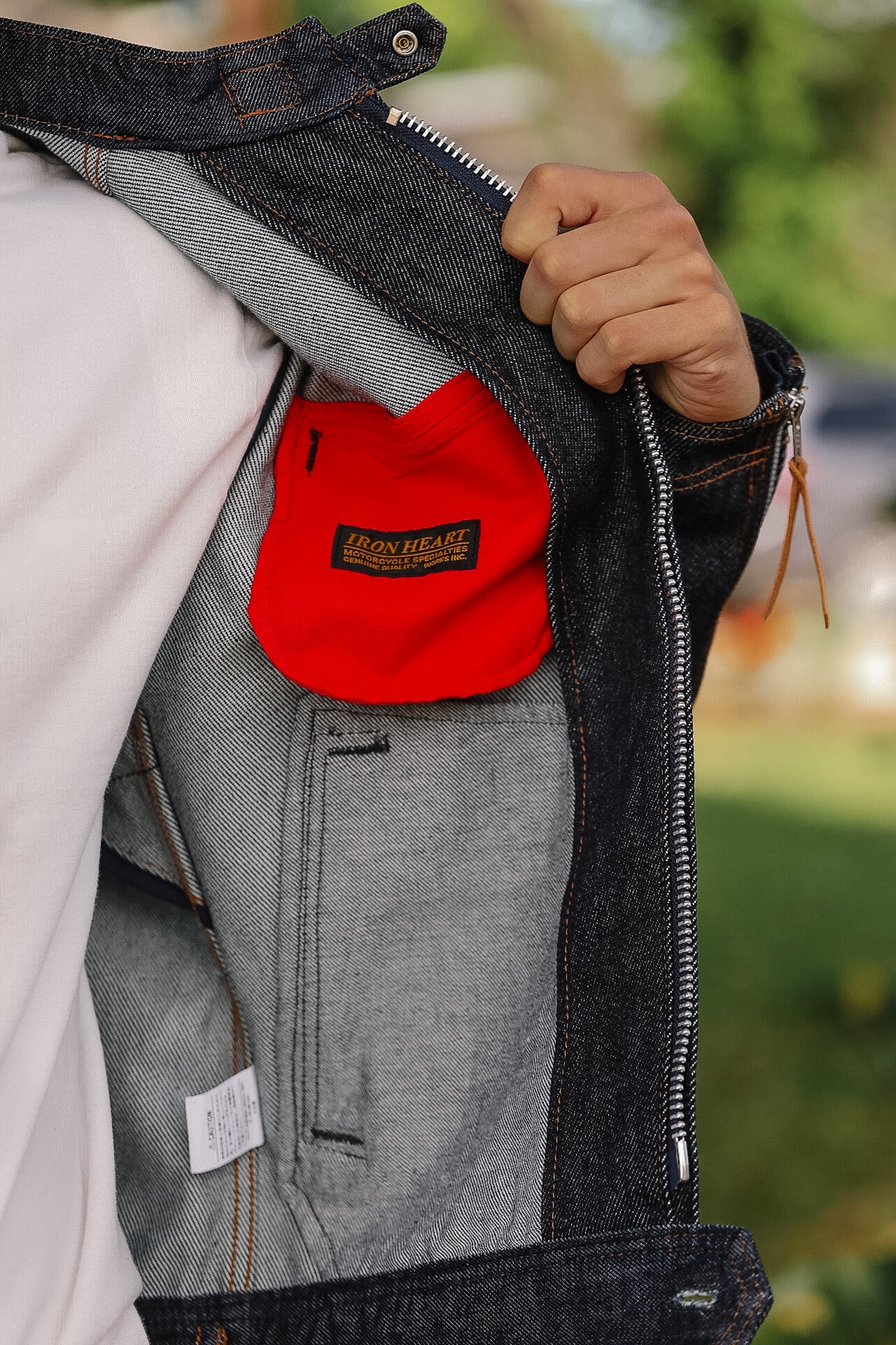 Person wearing a denim jacket with a red pouch featuring 'Iron Heart' branding.