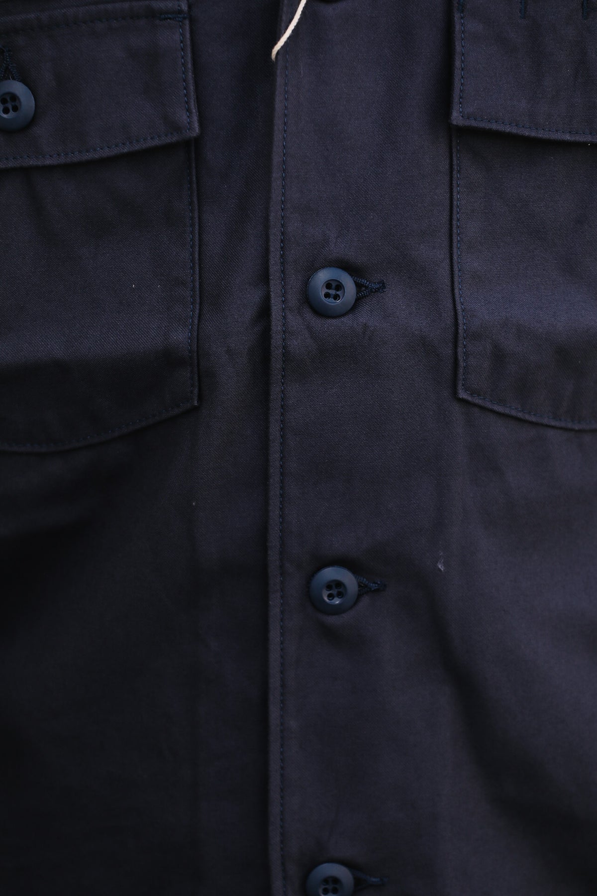 Close-up of a dark navy button-front shirt jacket with two flap chest pockets and matching dark buttons.