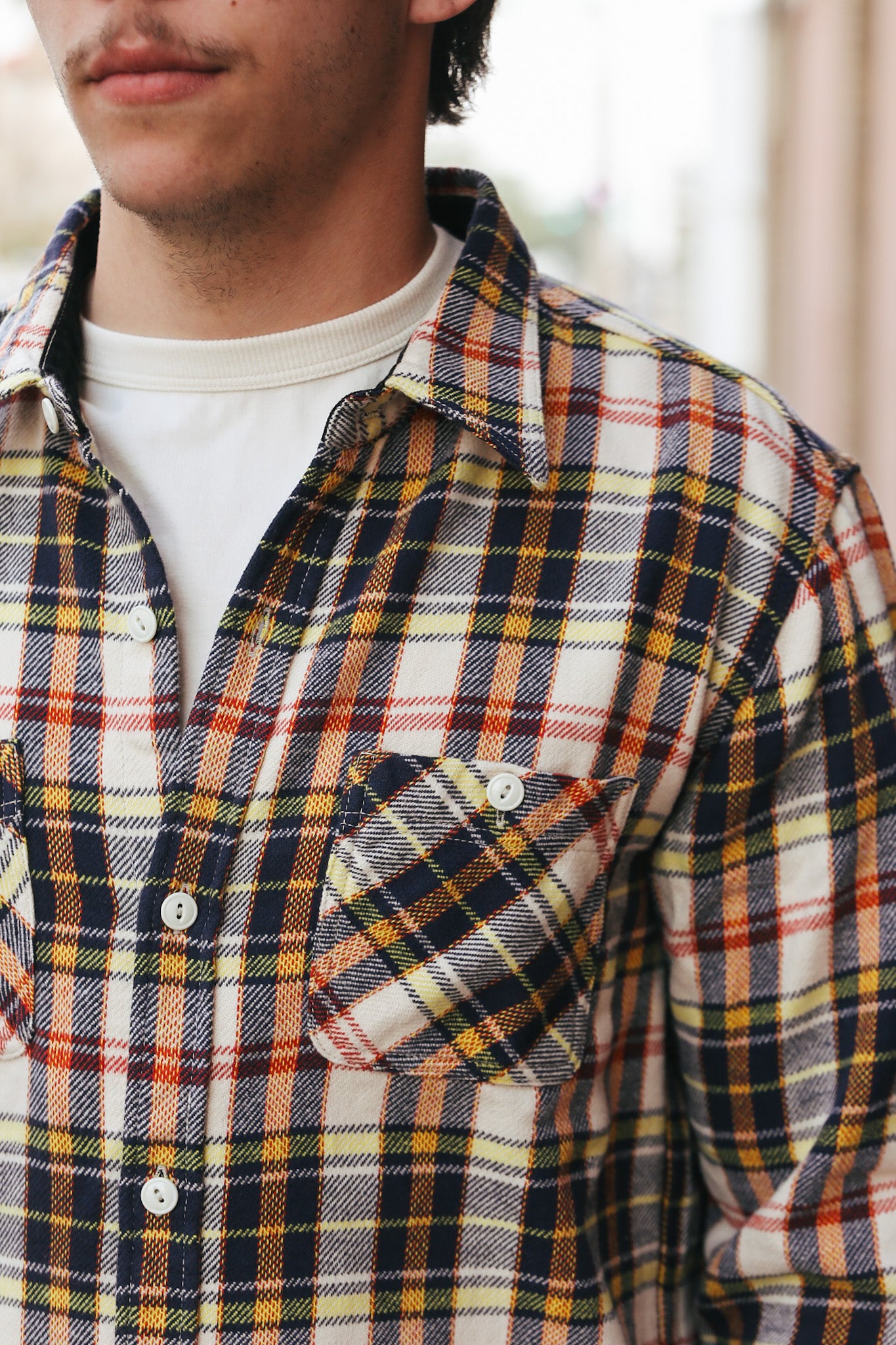 Person wearing a plaid shirt with a blurred background