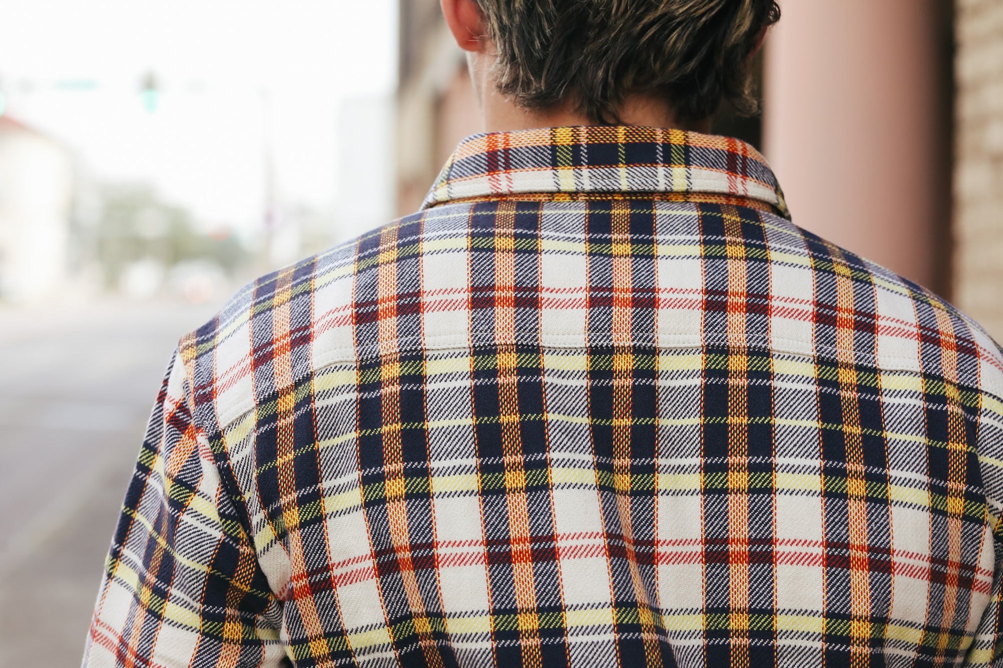 Person wearing a plaid shirt with a blurred background