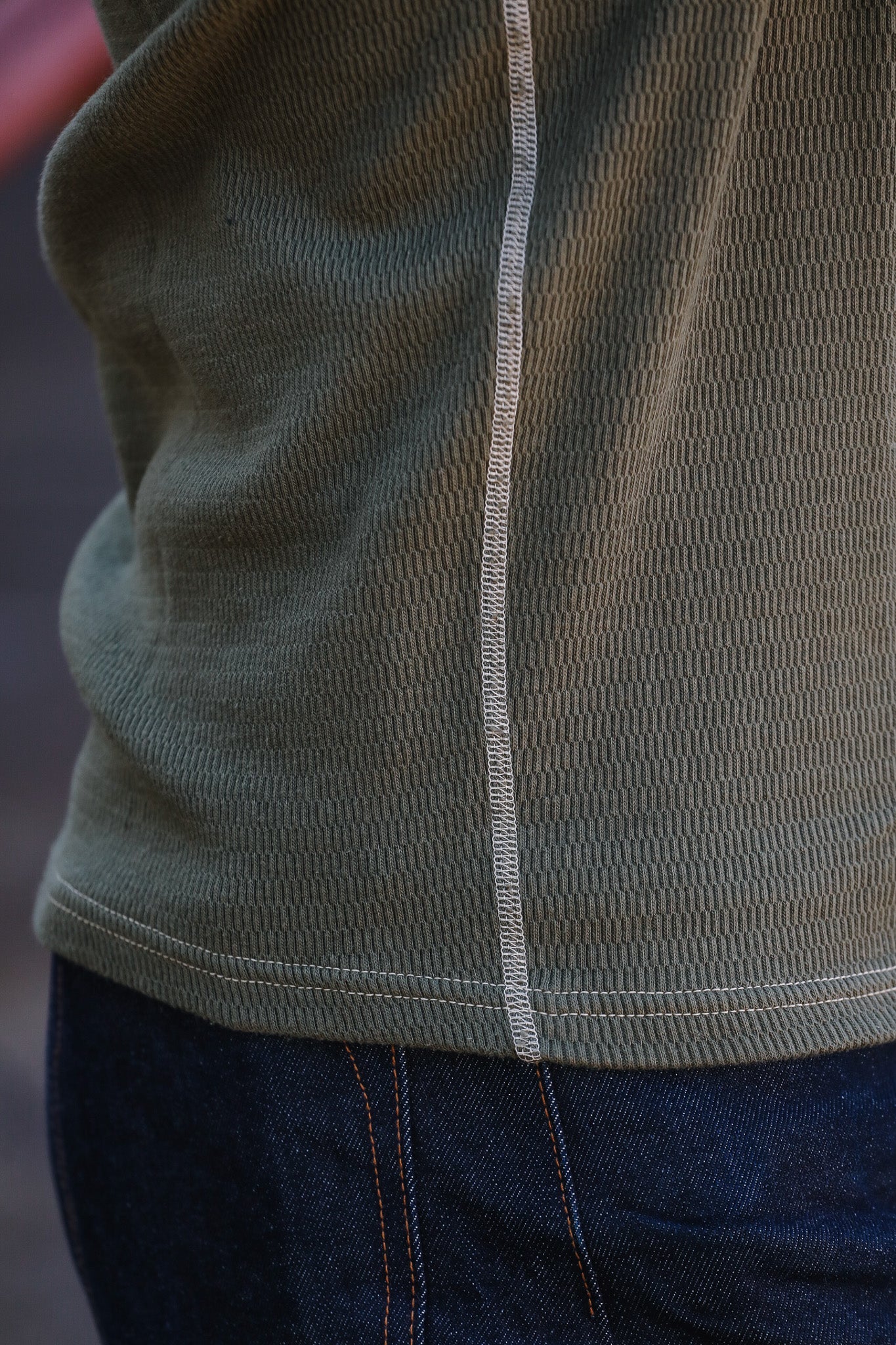 Close-up of a green jacket with a zipper and blue jeans.