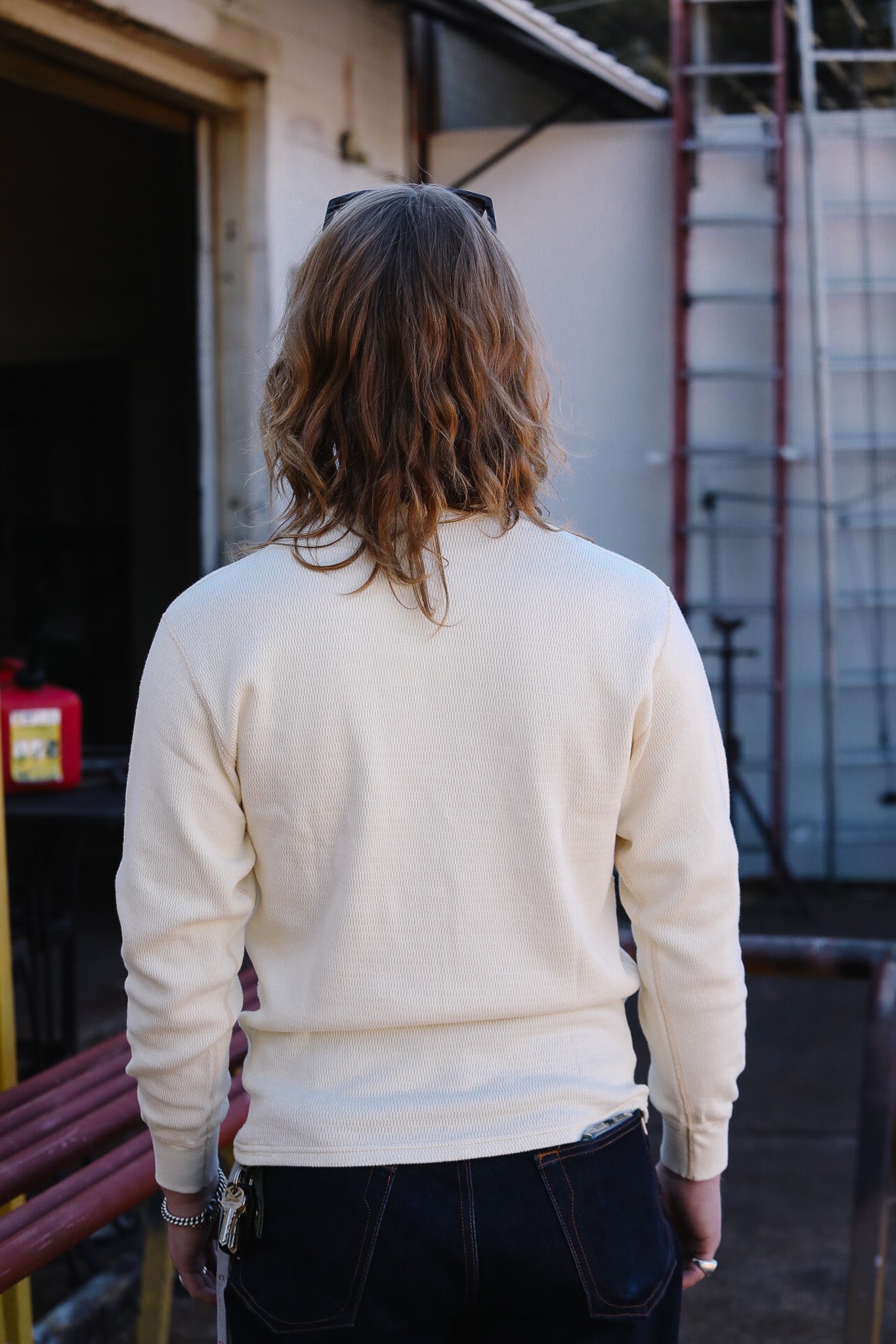 Person wearing a white sweater standing in an industrial setting