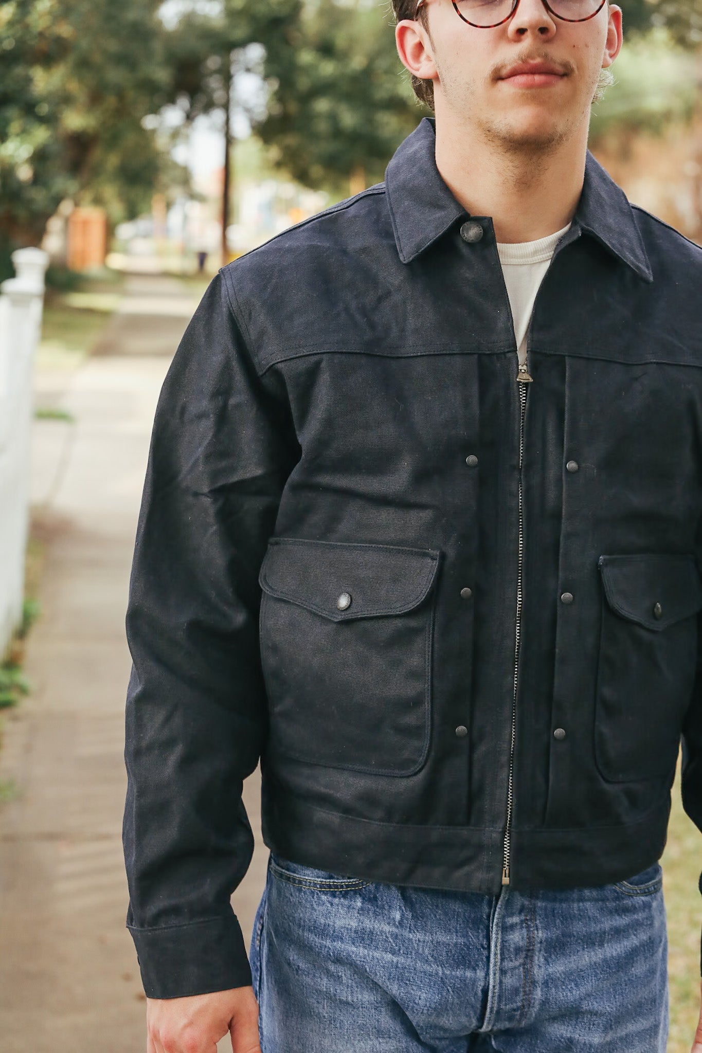 Person wearing a black jacket and blue jeans outdoors