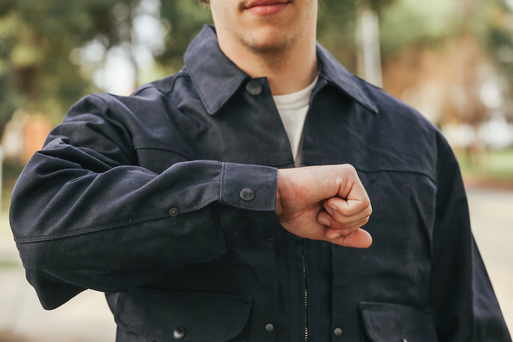 Person wearing a dark jacket with a blurred outdoor background