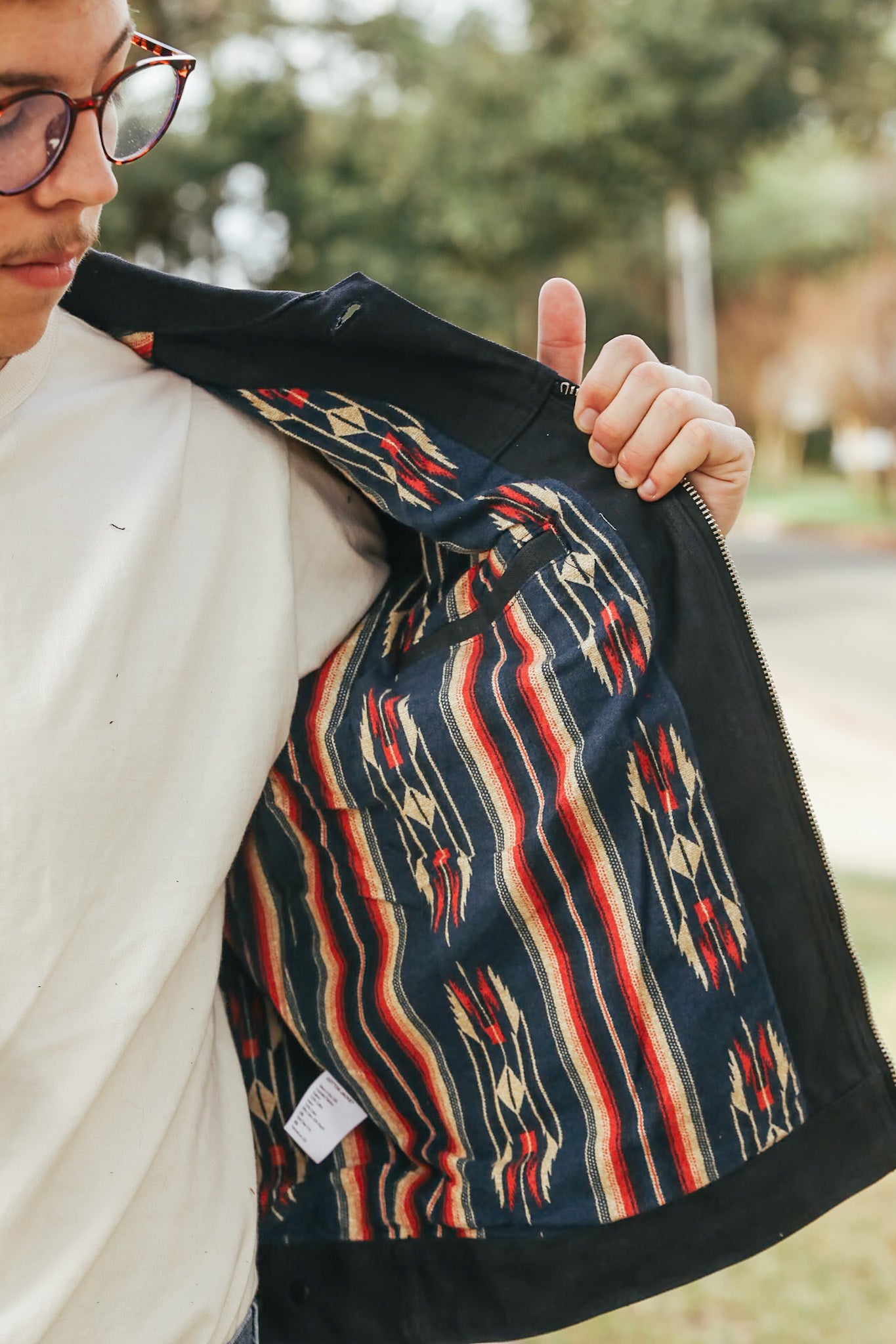 Person holding a patterned jacket with a blurred outdoor background