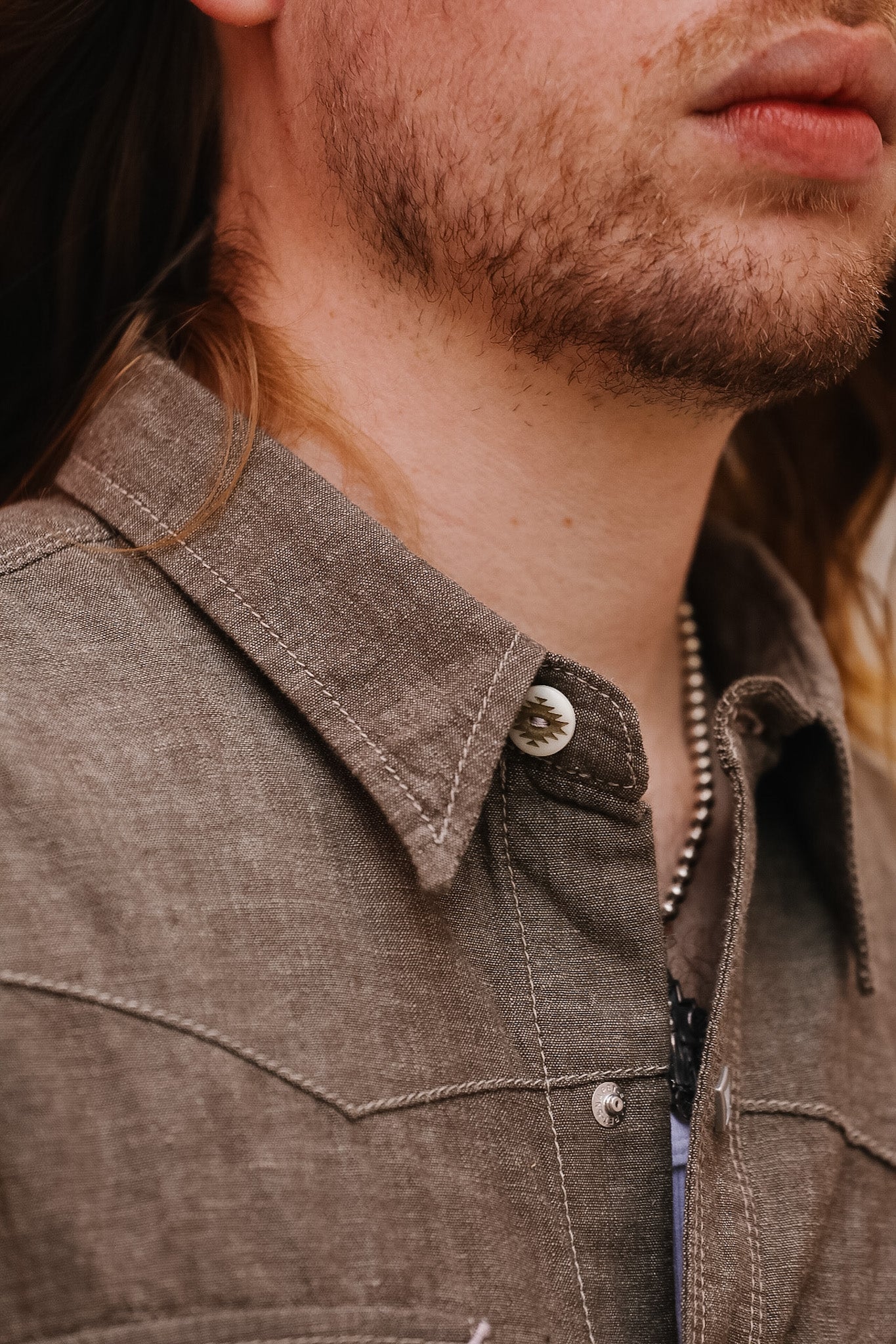 Close-up of a person wearing a brown jacket with a collar.