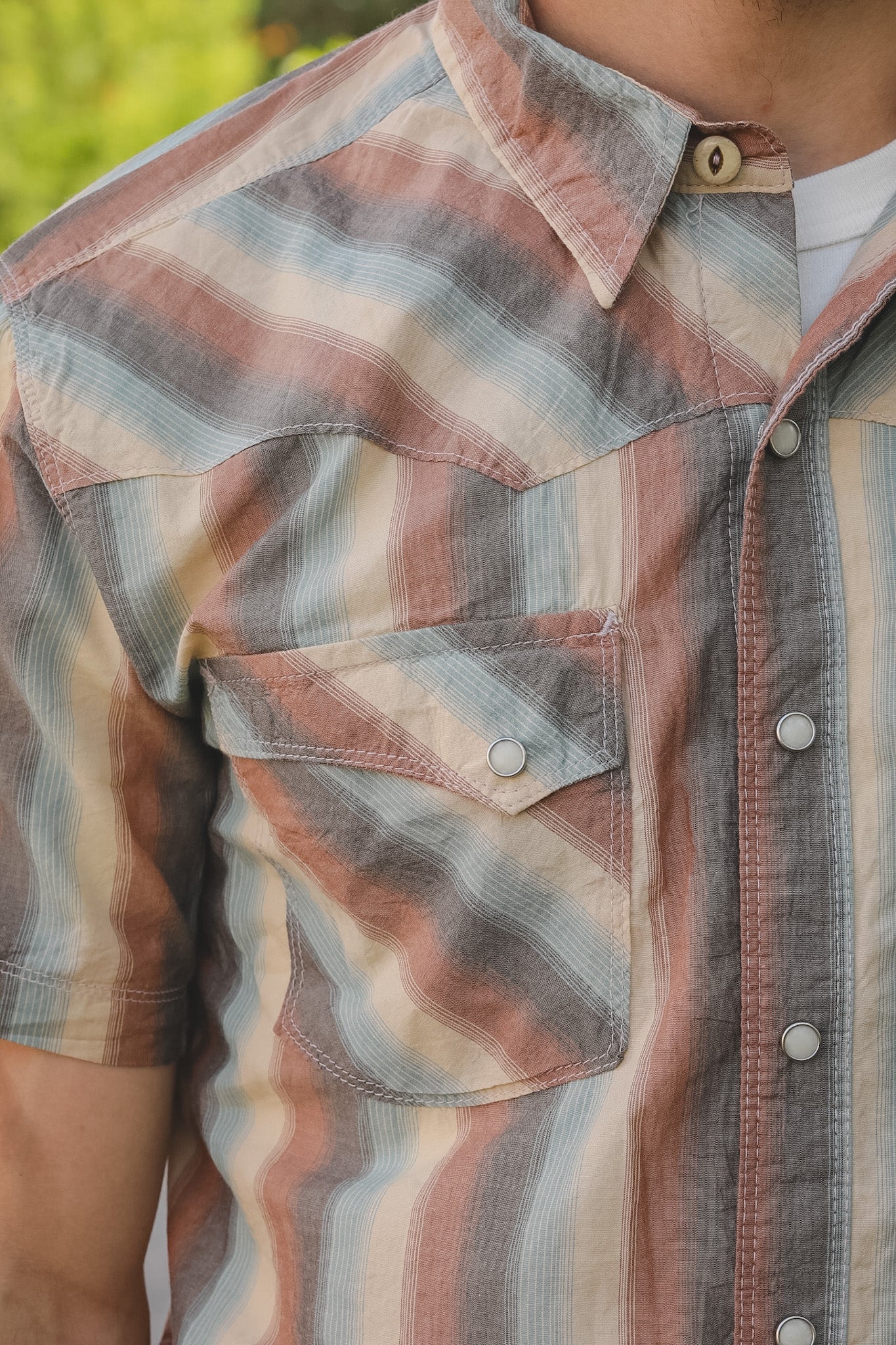 Close-up of a person wearing a plaid shirt with a blurred green background