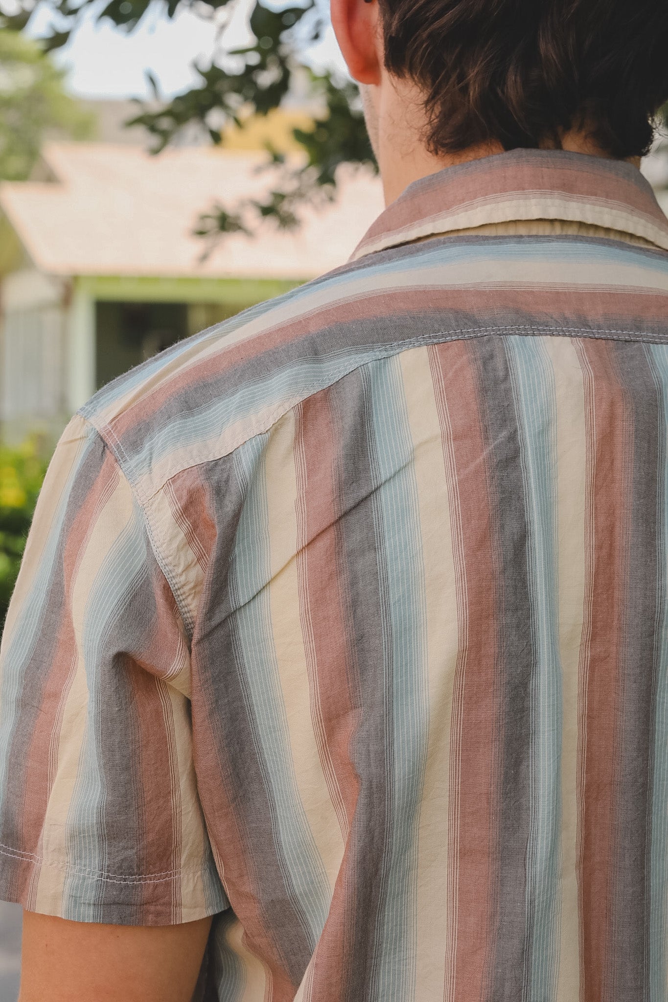 Person wearing a striped shirt with a blurred background