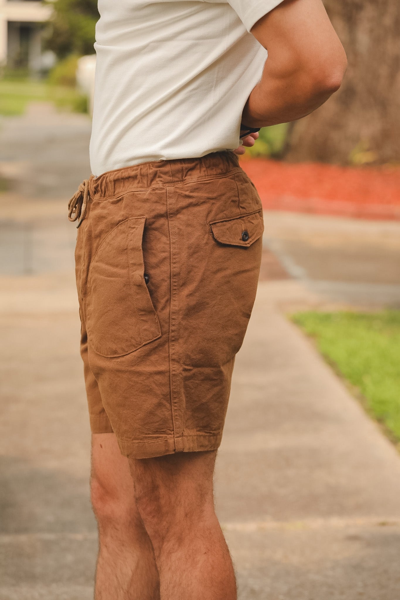 Person wearing brown shorts and a white shirt outdoors