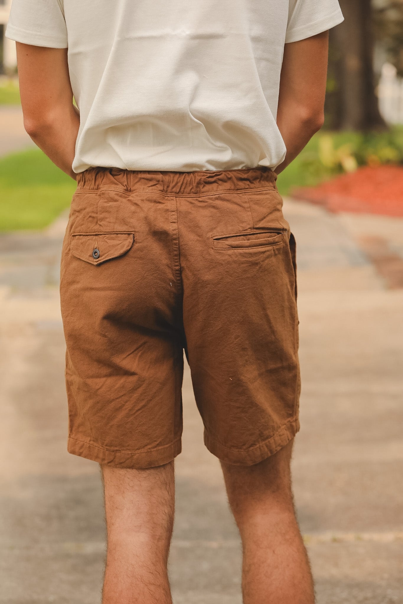 Person wearing brown shorts and a white shirt outdoors
