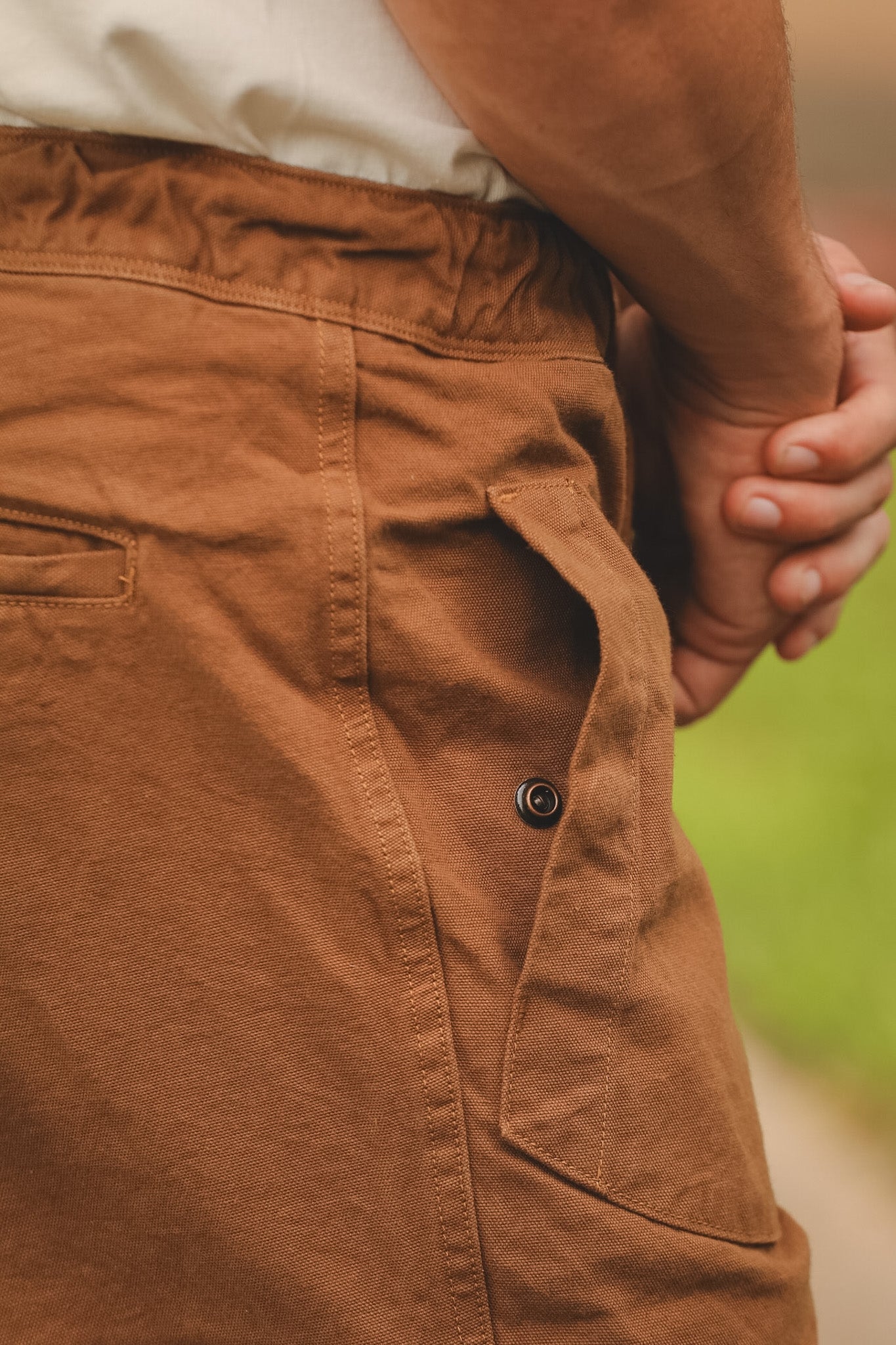 Brown pants with a button detail on a blurred natural background