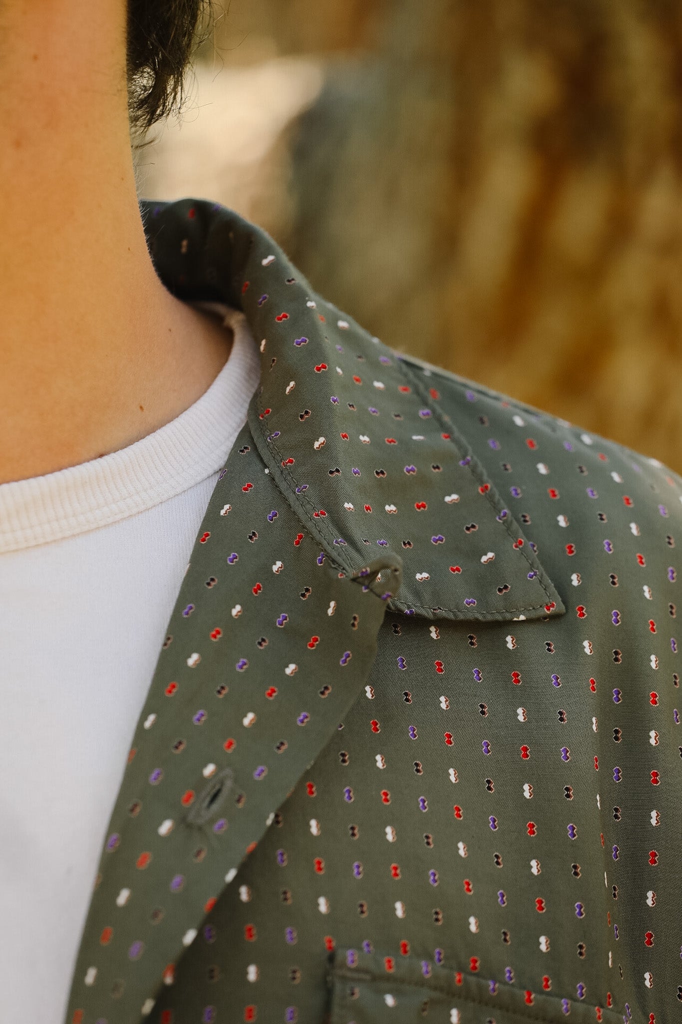 Close-up of a person wearing a green patterned jacket with a blurred background