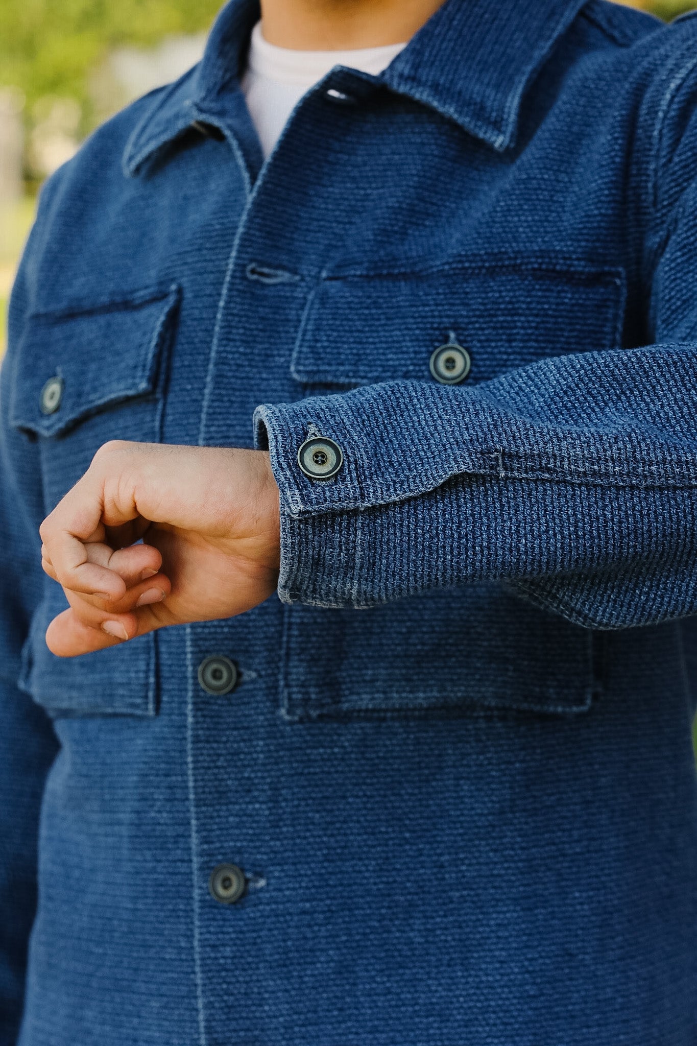 Close-up of a person wearing a blue corduroy jacket with a blurred background