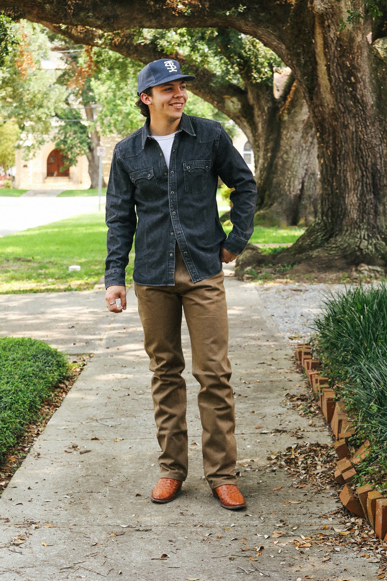 Man standing on a sidewalk with trees and greenery in the background