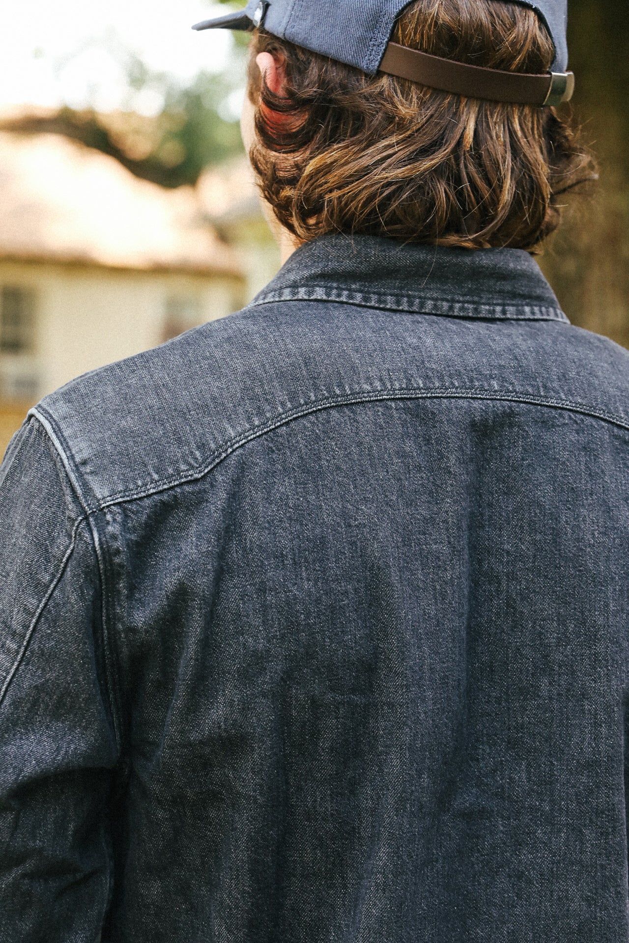 Person wearing a denim jacket and cap with a blurred background