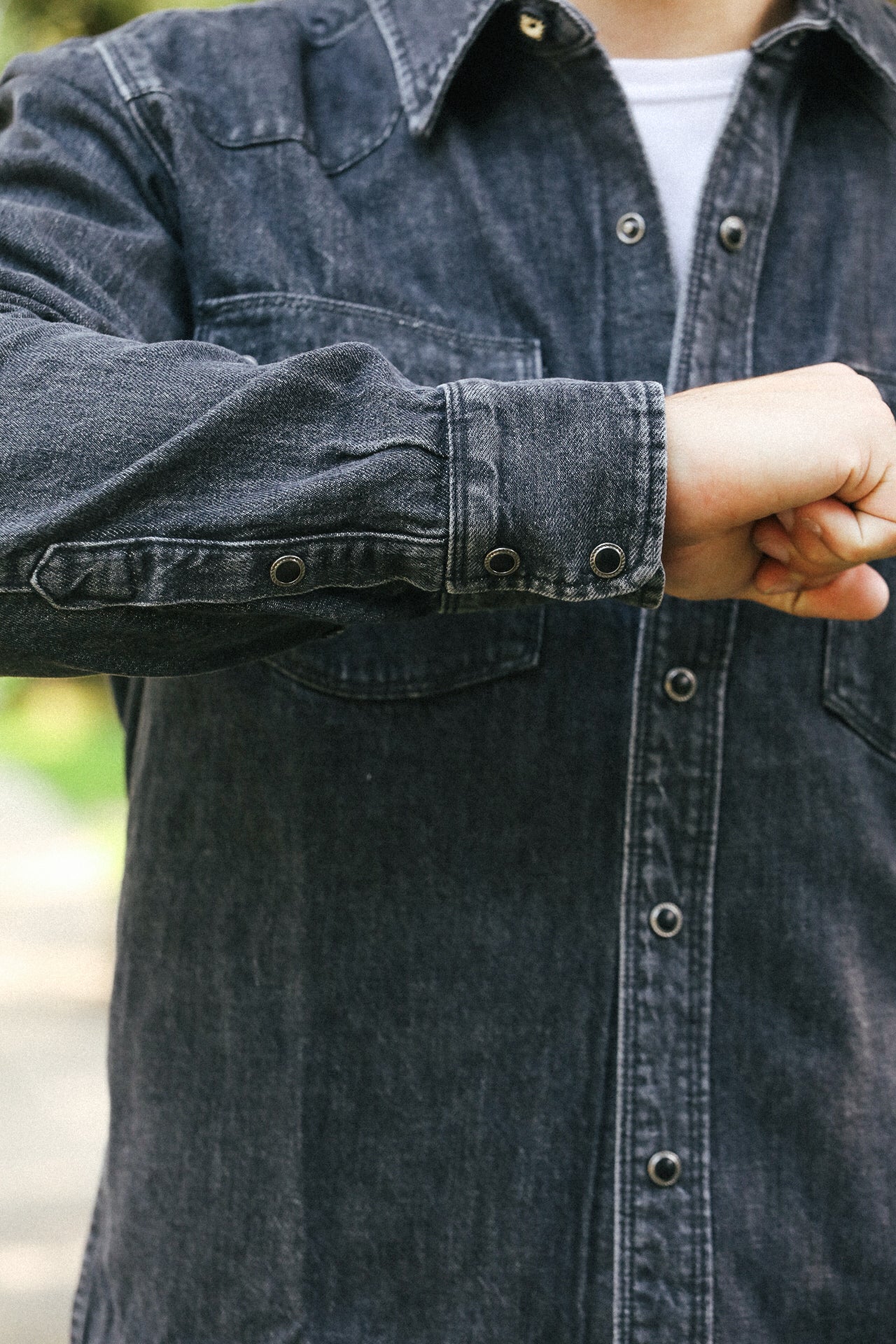 Person wearing a dark denim shirt with a blurred background