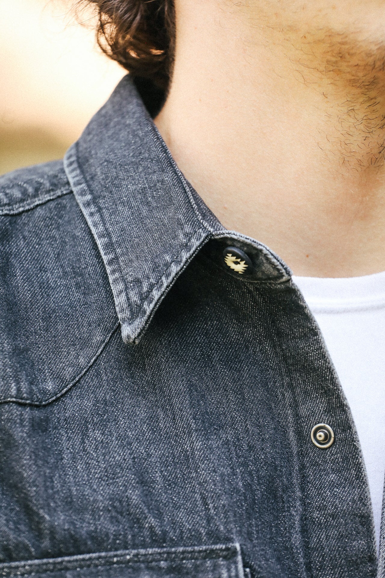 Close-up of a person wearing a denim jacket with a blurred background