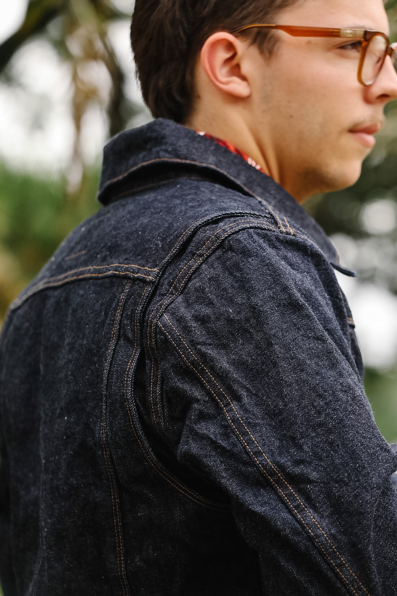 Person wearing a denim jacket with a blurred outdoor background