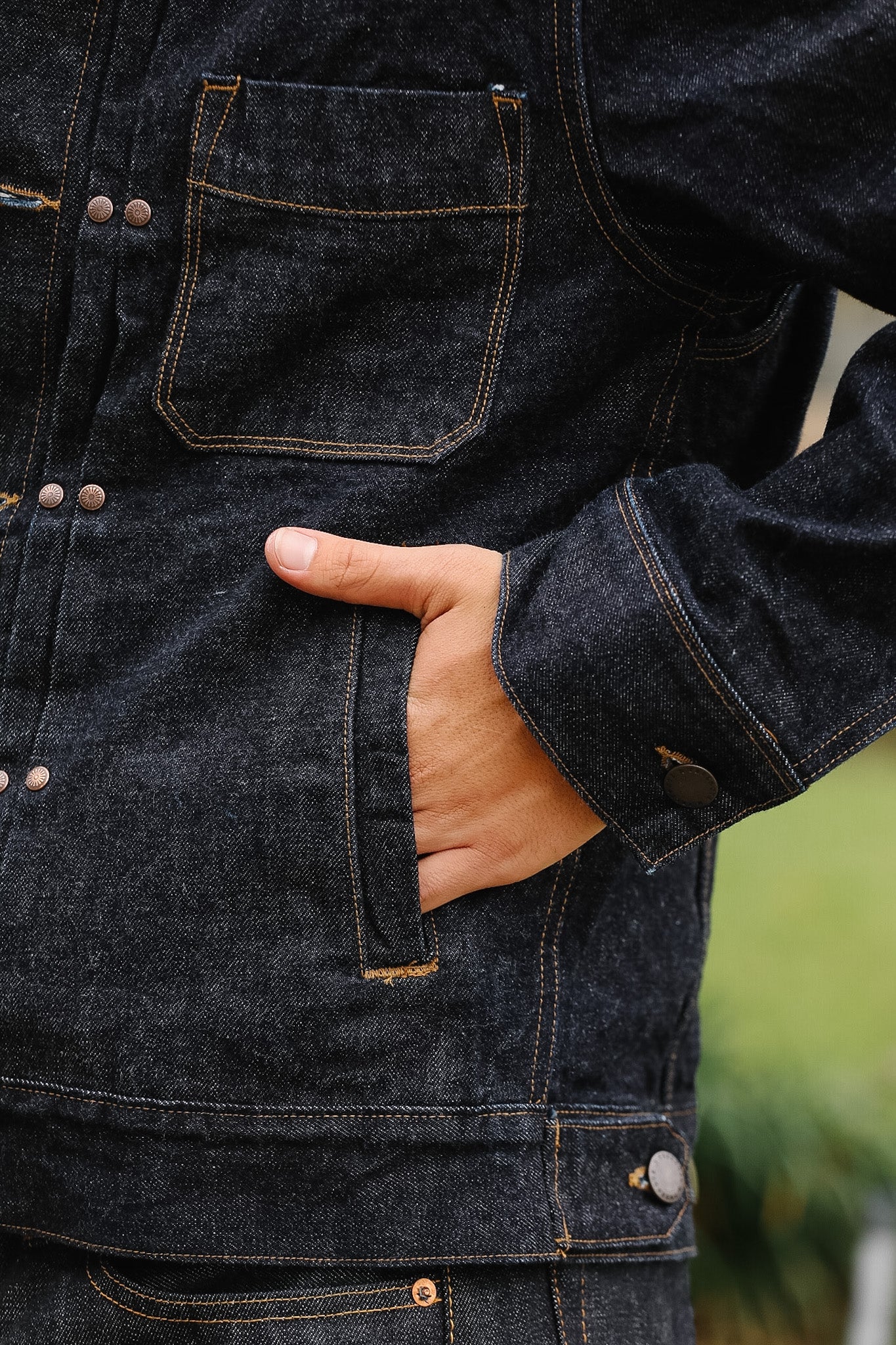 Close-up of a person wearing a dark denim jacket with a blurred background