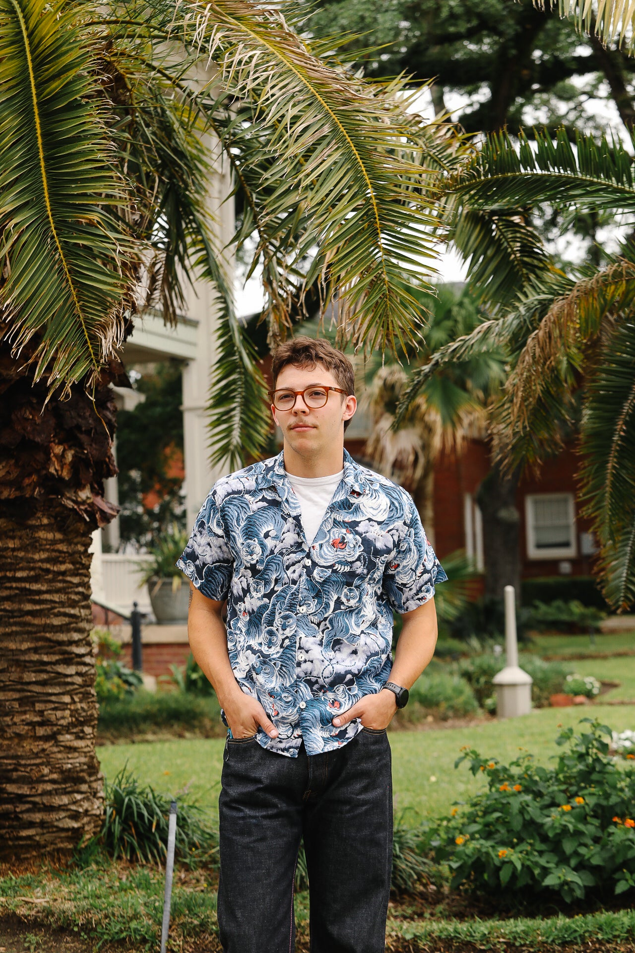 Man wearing a floral shirt standing in a garden with palm trees