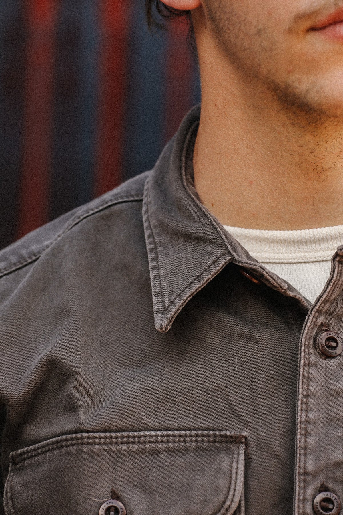 man wearing brown shirt standing in front of metal gate