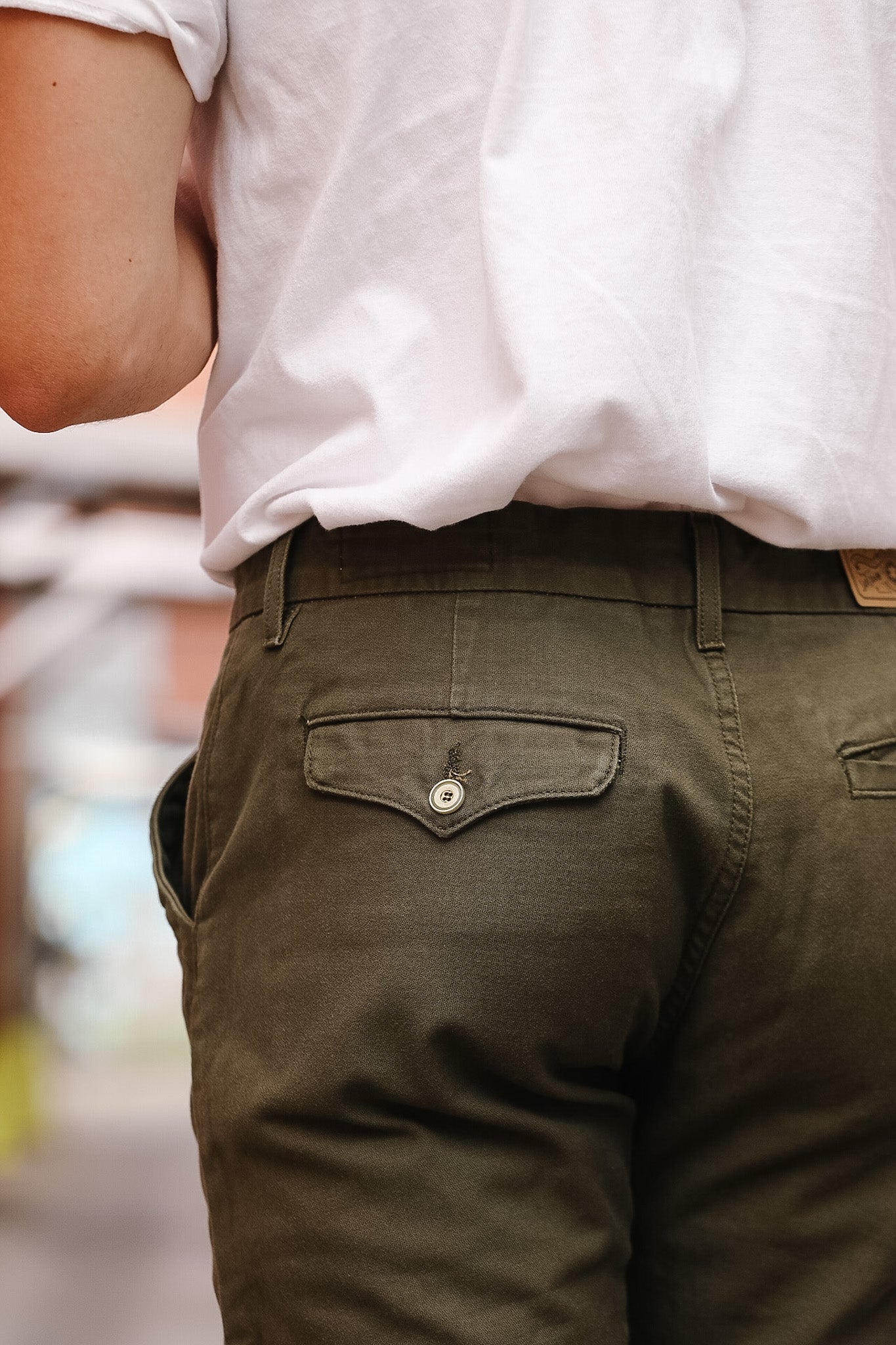Person wearing a white shirt and green pants with a blurred background