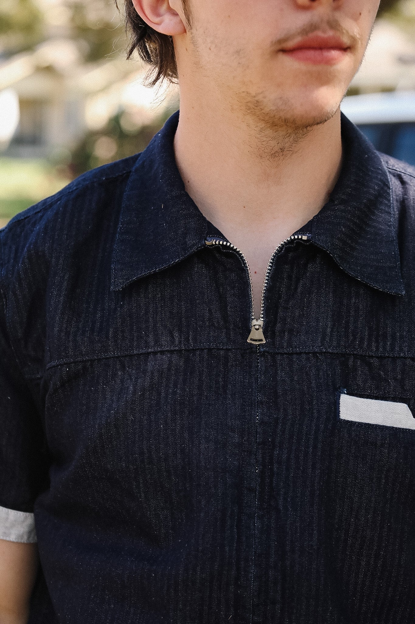 Close-up of a person wearing a dark blue corduroy shirt with a zipper.