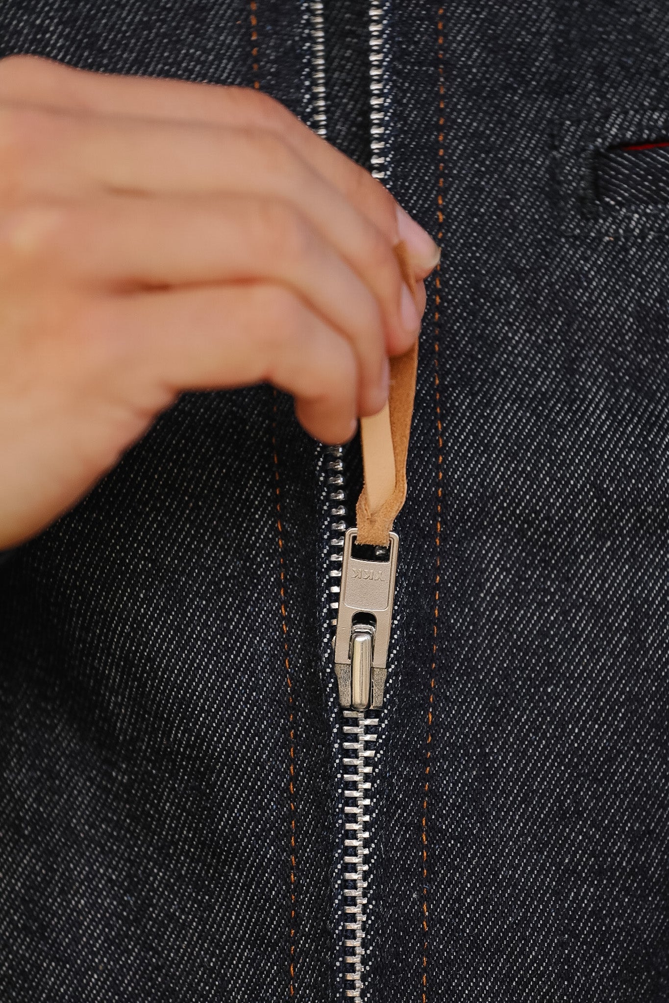 Hand zipping a black denim jacket