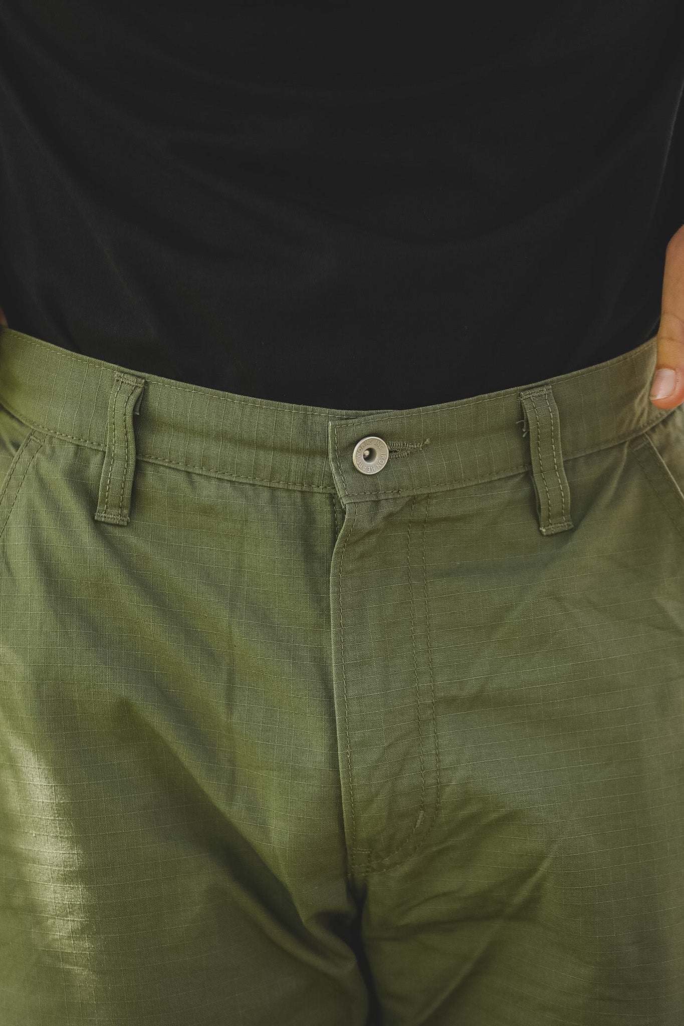 Person wearing green pants with a black shirt underneath