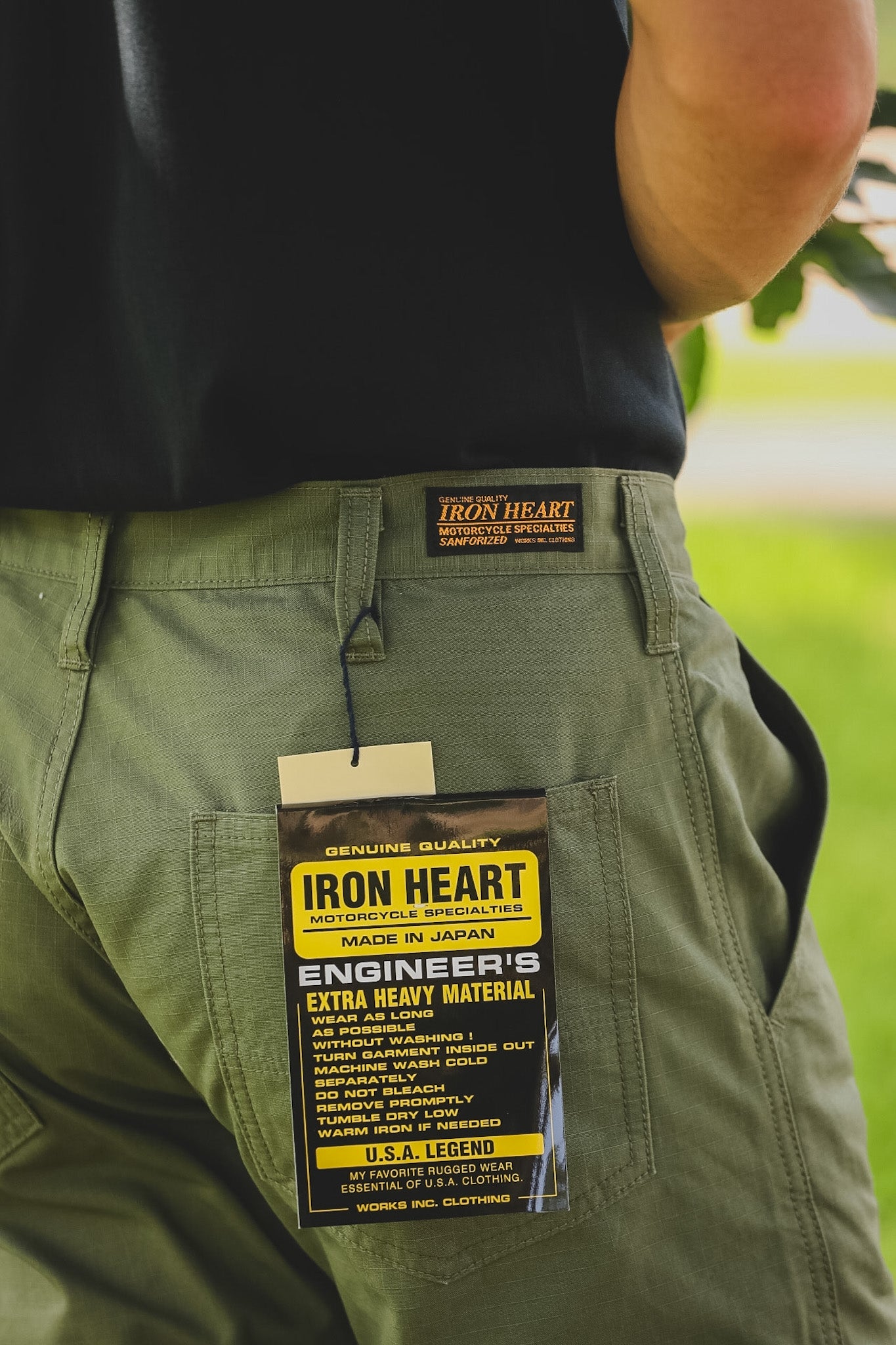 Green pants with Iron Heart label on a blurred natural background