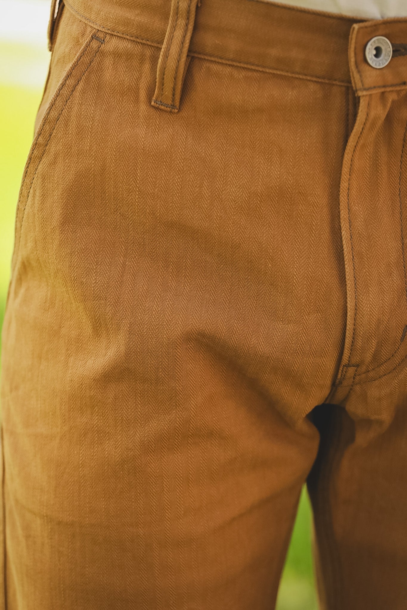 Close-up of brown pants with a blurred green background