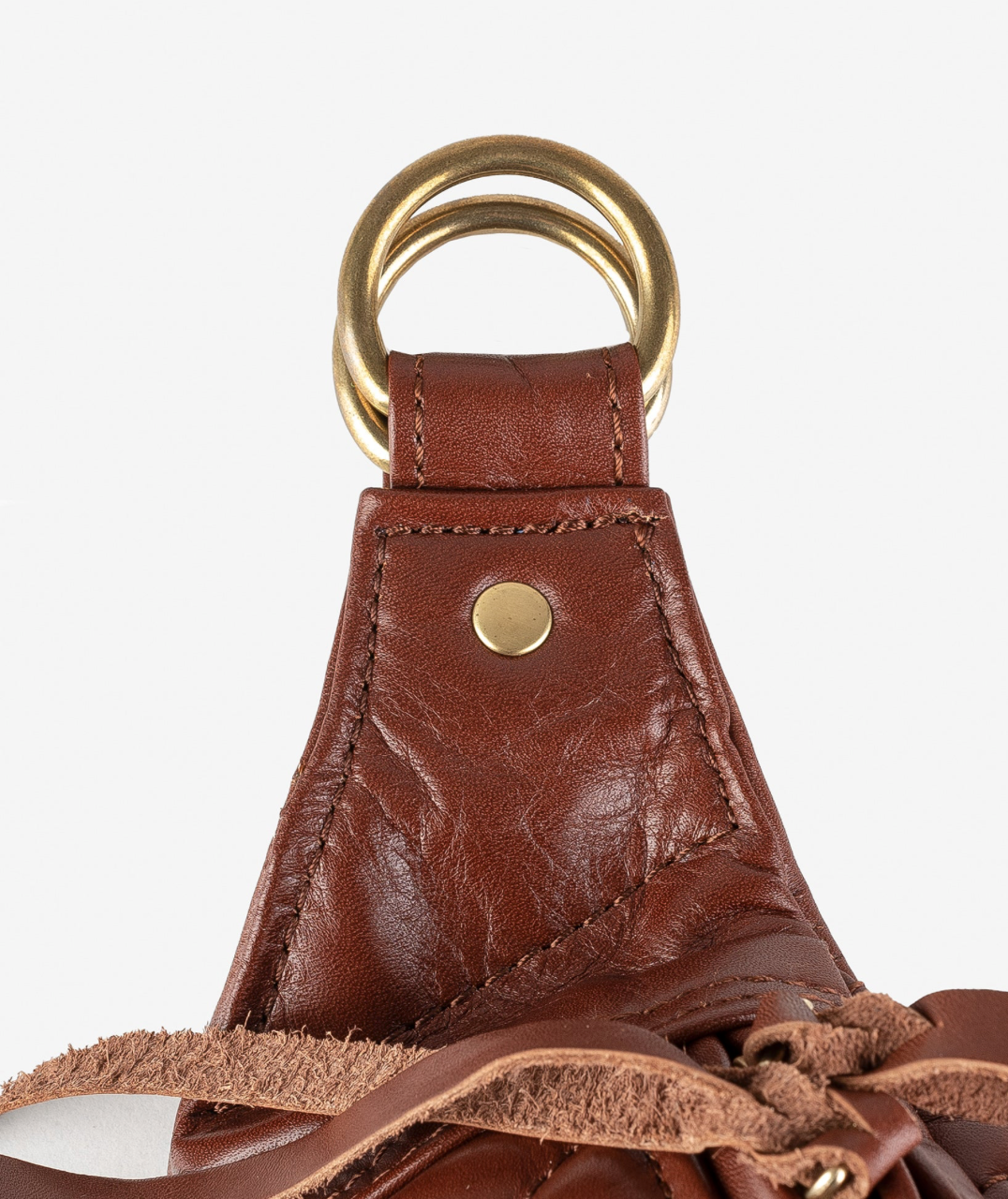 Close-up of a brown leather bag handle with gold hardware on a light gray background
