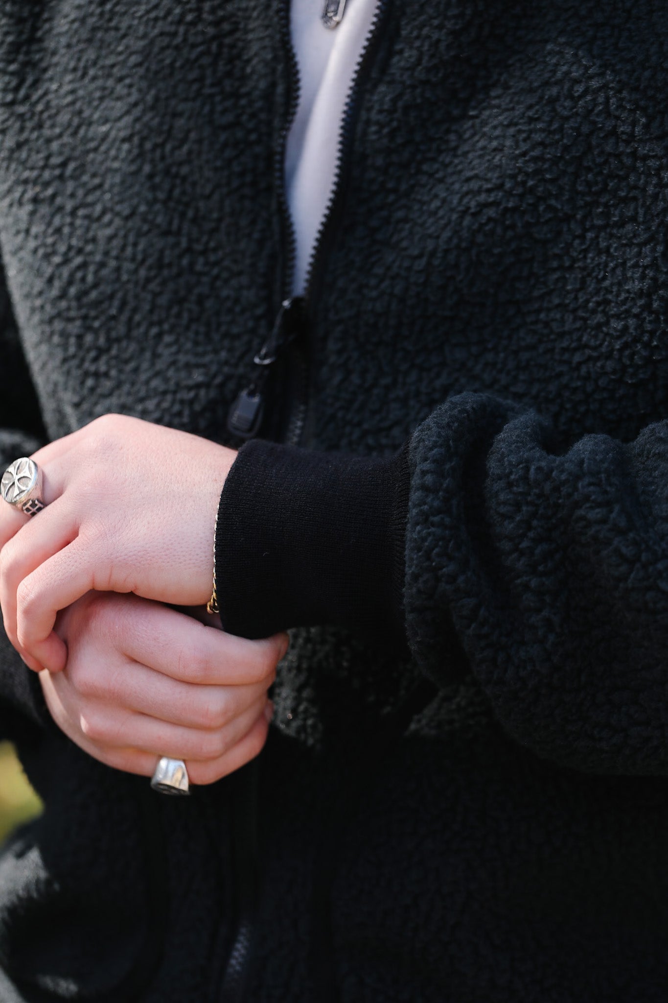 Close-up of hands wearing rings with a black jacket background
