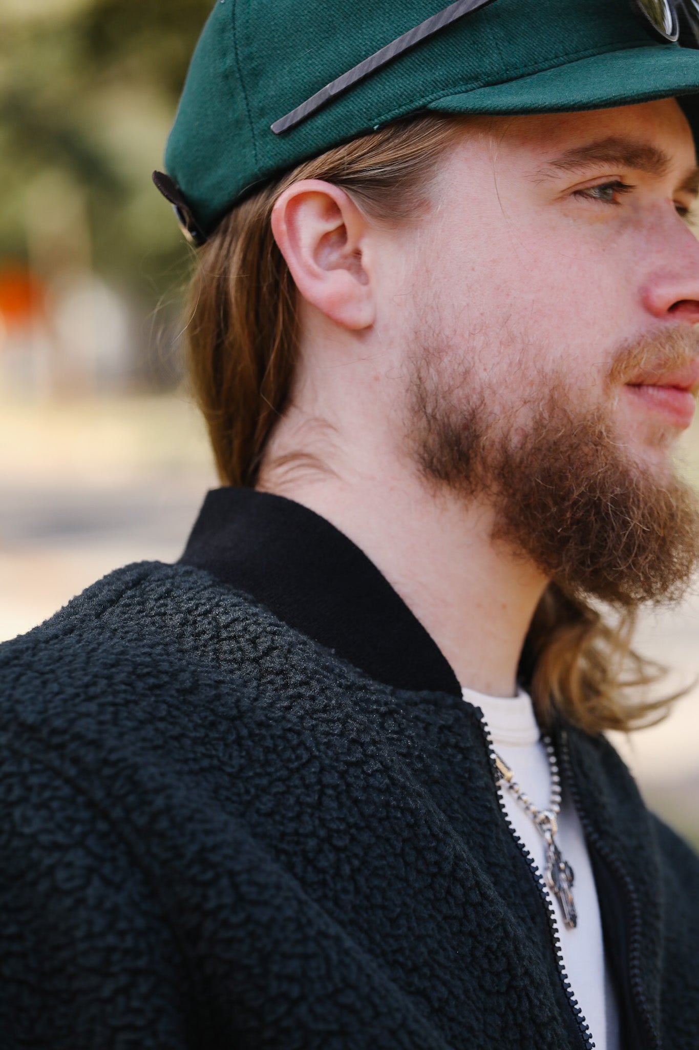 Man wearing a green cap and dark jacket with a blurred background
