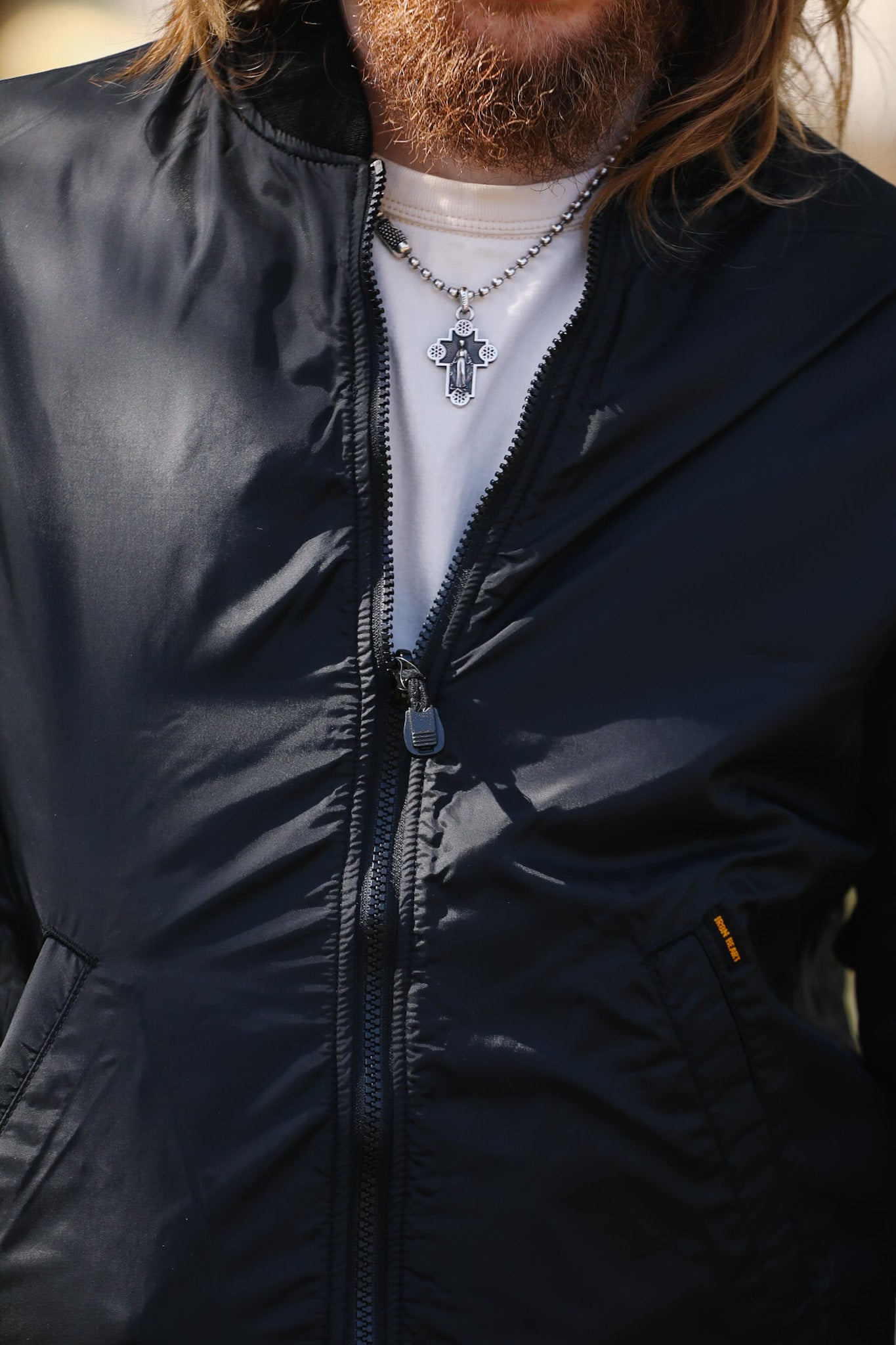 Person wearing a black jacket with a visible cross necklace.