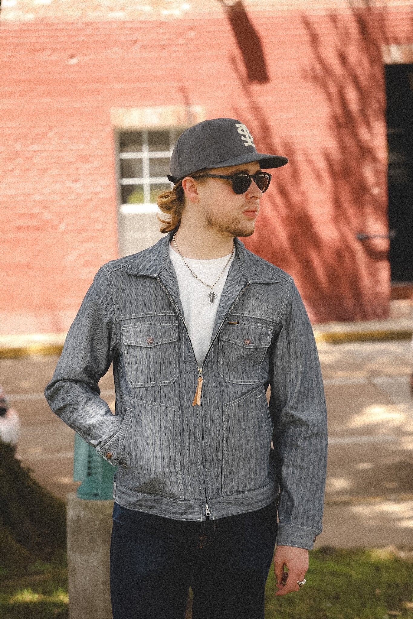 man wearing denim stripe jacket outdoors with a blurred background 