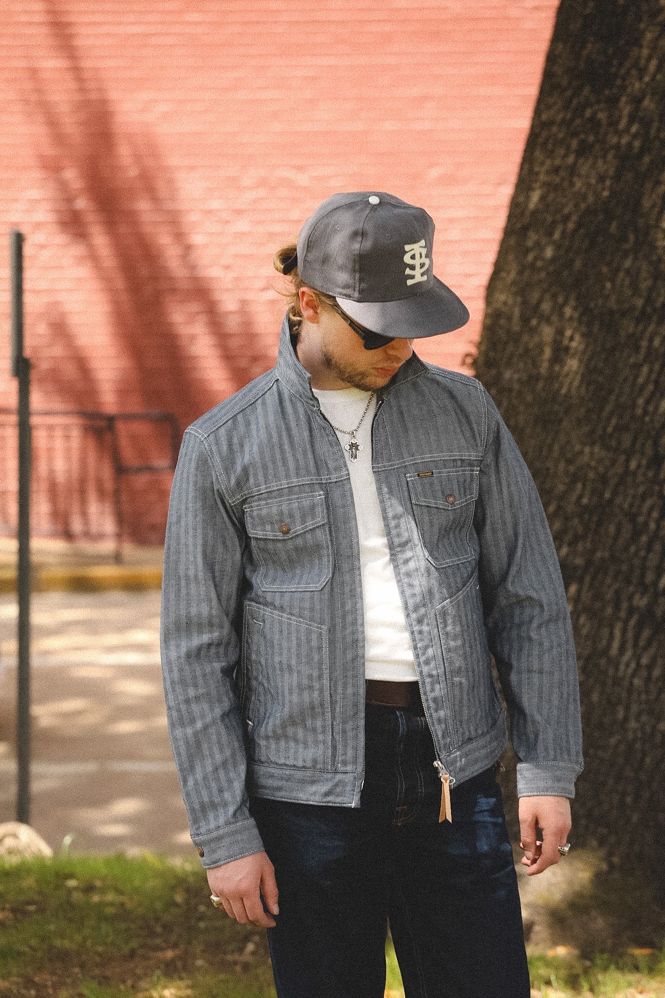 man wearing denim stripe jacket outdoors with a blurred background 