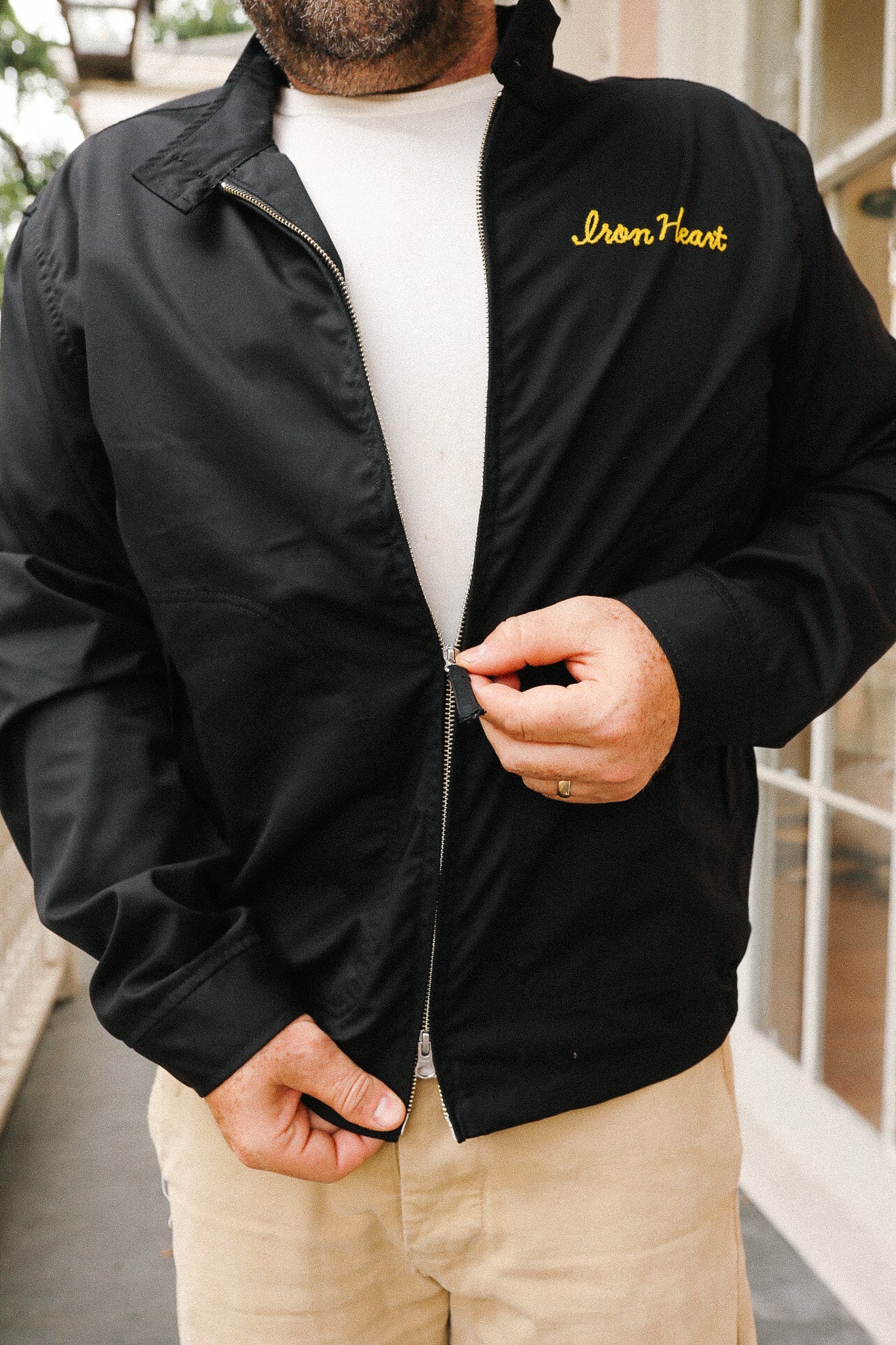 Person wearing a black jacket with 'Iron Heart' branding, standing indoors.