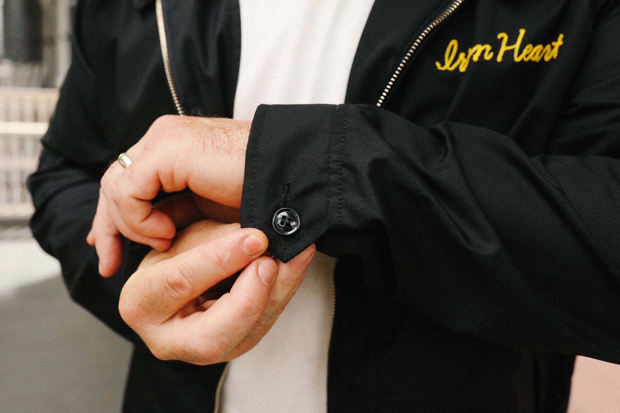 Person wearing a black jacket with 'Iron Heart' branding, adjusting the sleeve.