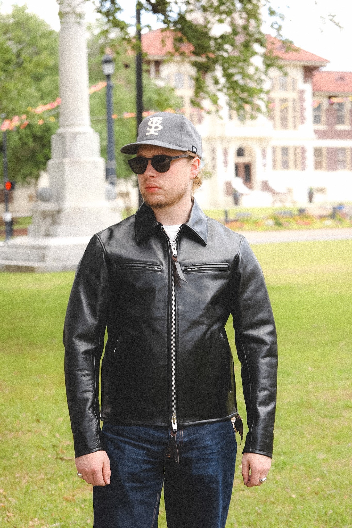 A person wearing a black horsehide rider's jacket with a collar, standing outdoors.