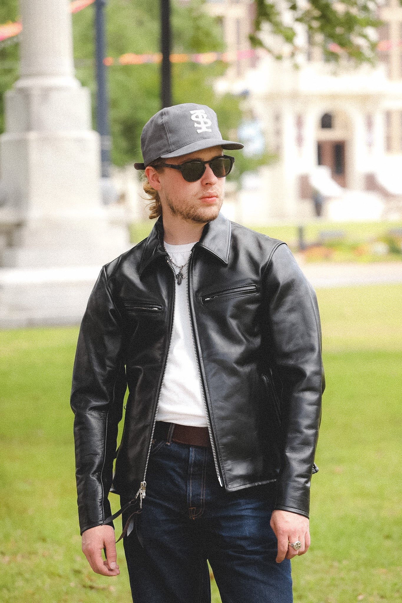 A person wearing a black horsehide rider's jacket with a collar, standing outdoors.